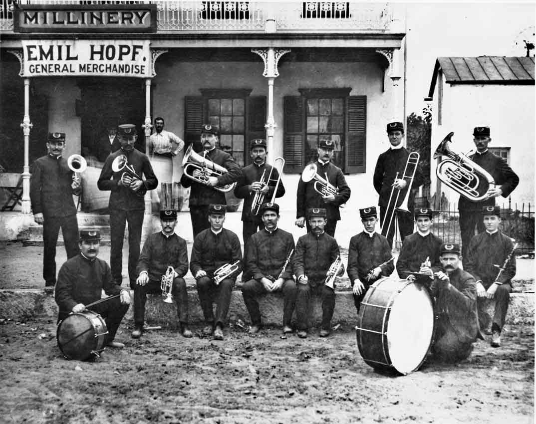 A group of people stand in marching band outfits holding instruments