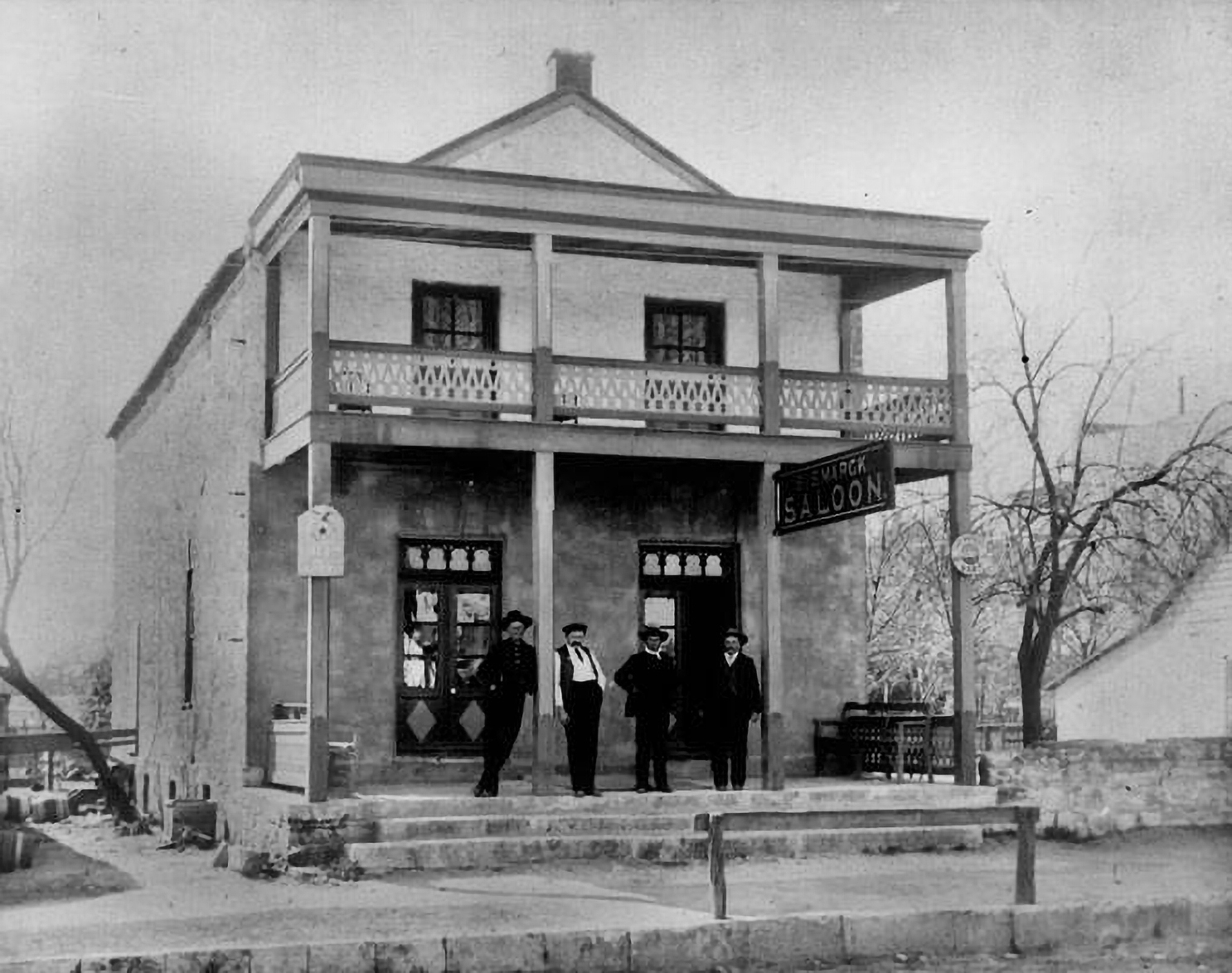 A group of men in suits stand in front of an old saloon