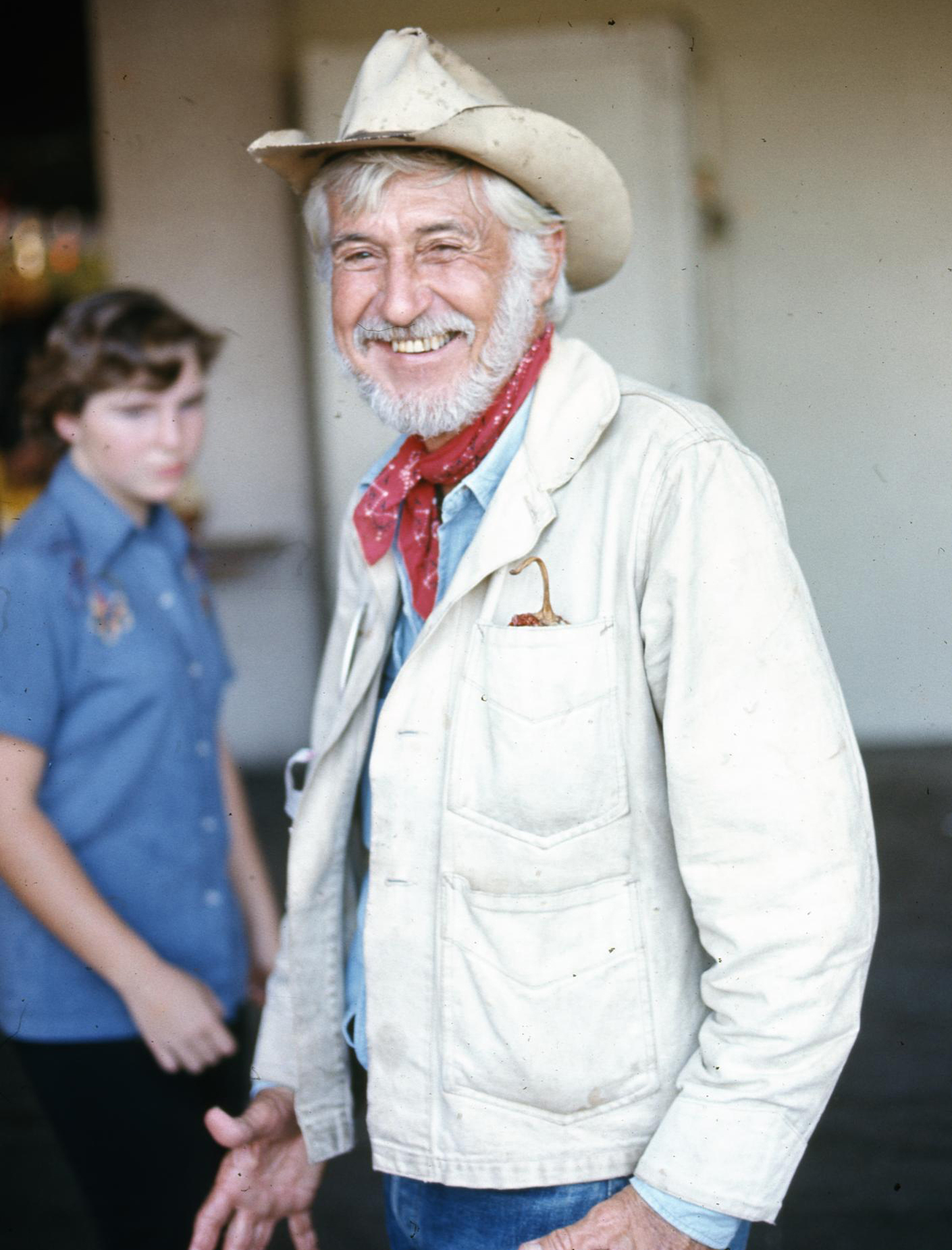A man in a red bandana and cowboy hat smiles for the camera