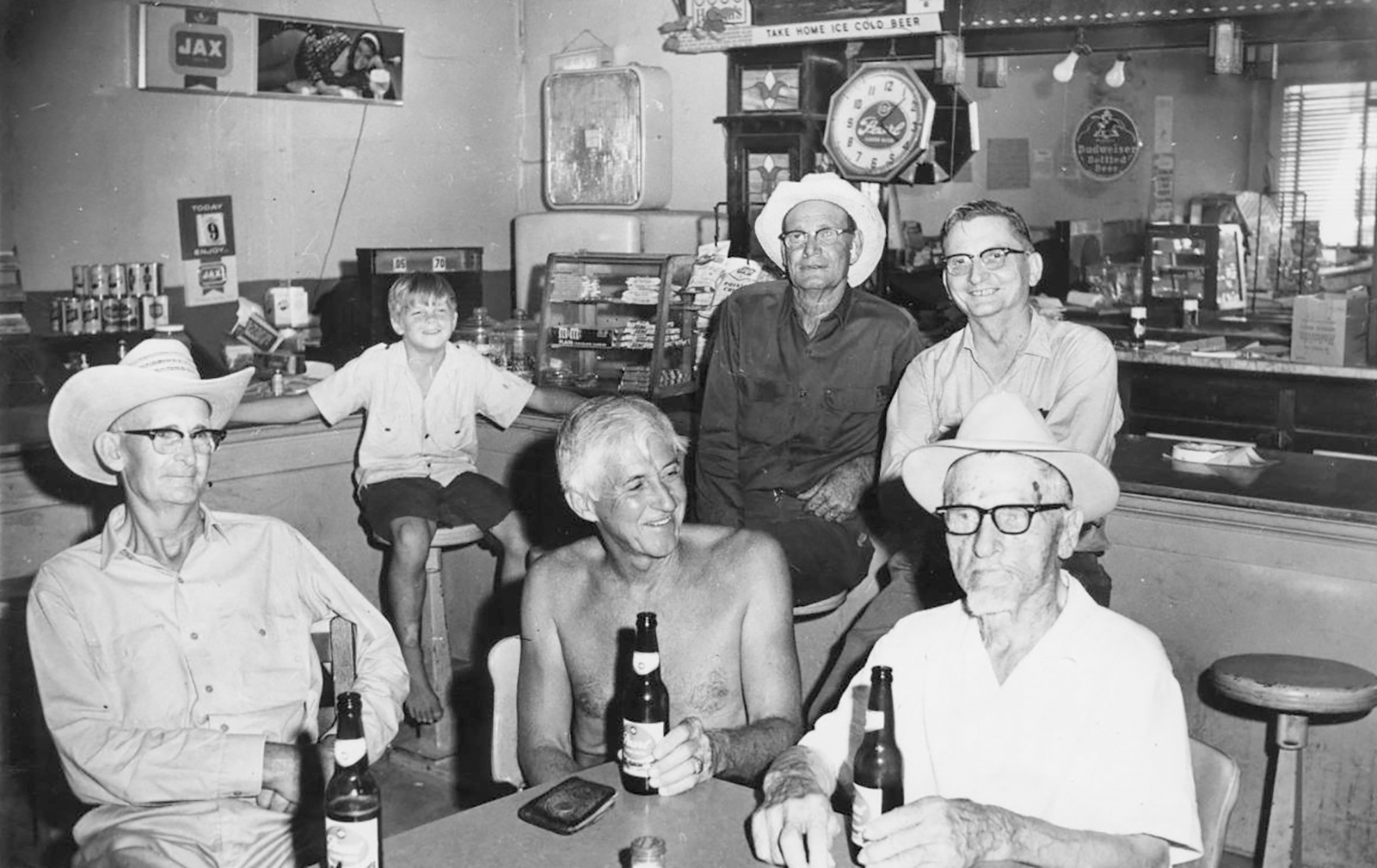 A group of men holding beers sit in a bar