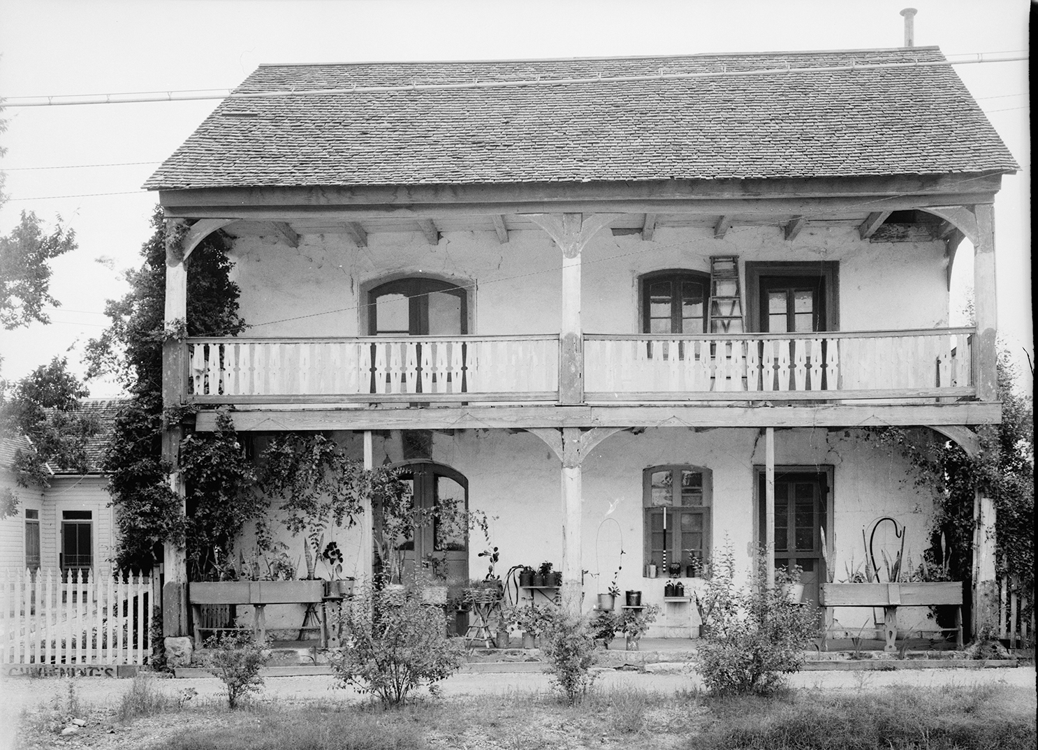 The outside of a two-story house with plants in front