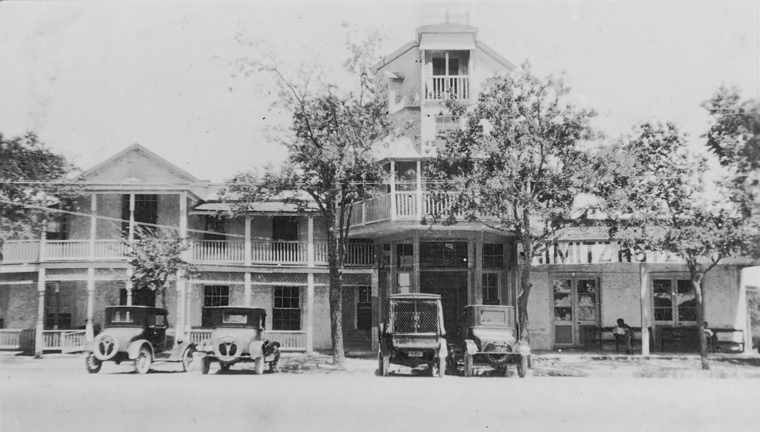 The outside of a three-story hotel with cars parked in front