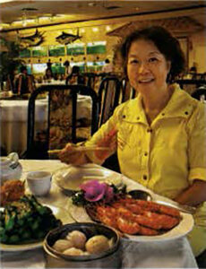 Dorothy Huang smiling with a table full of dim sum 