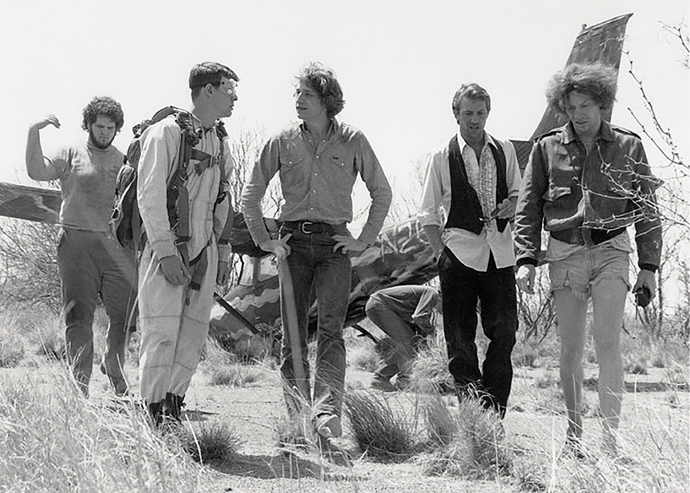 A black and white screen capture of a group of men in front of an airplane