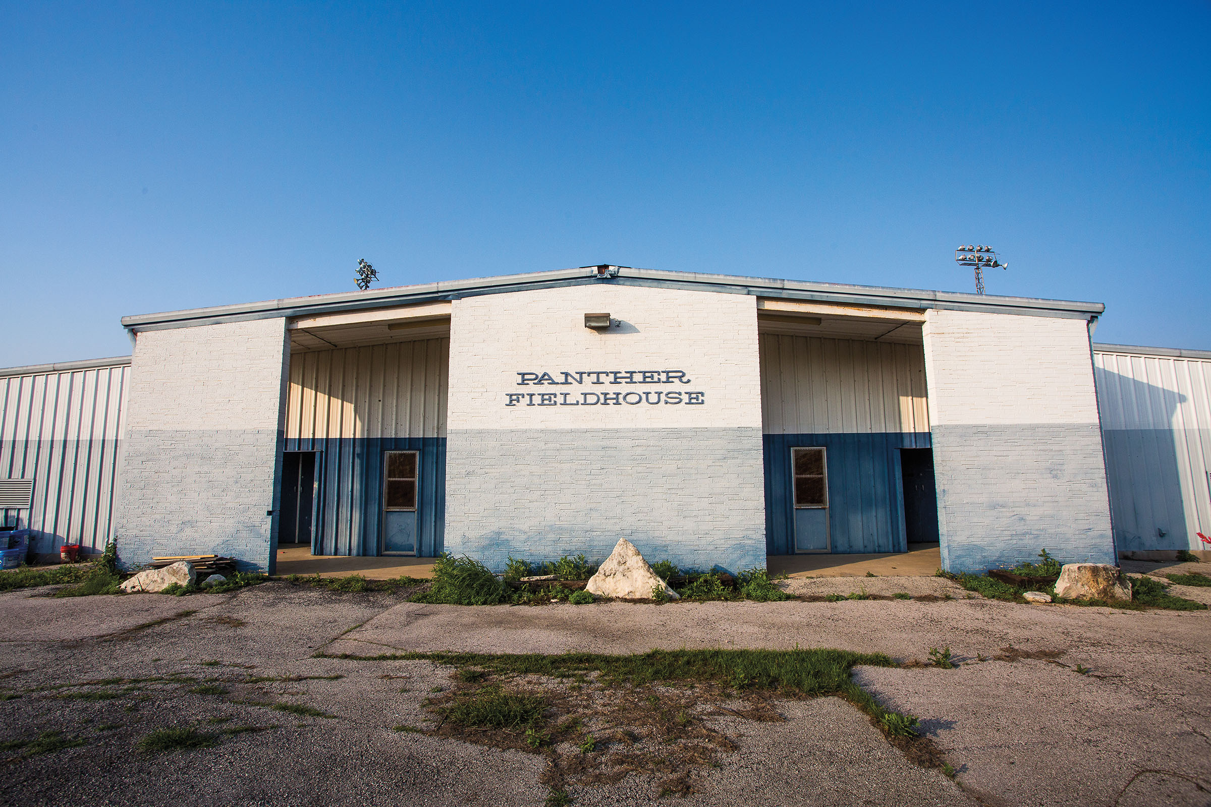 The outside of a gray and white painted building with letters reading "Panther Fieldhouse"