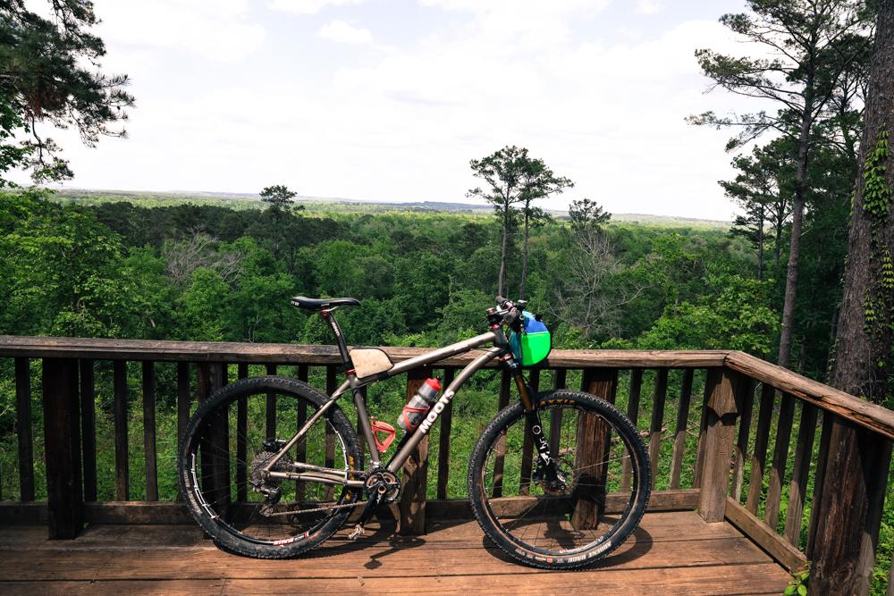 A mountain bike on a railing above a green forest canopy