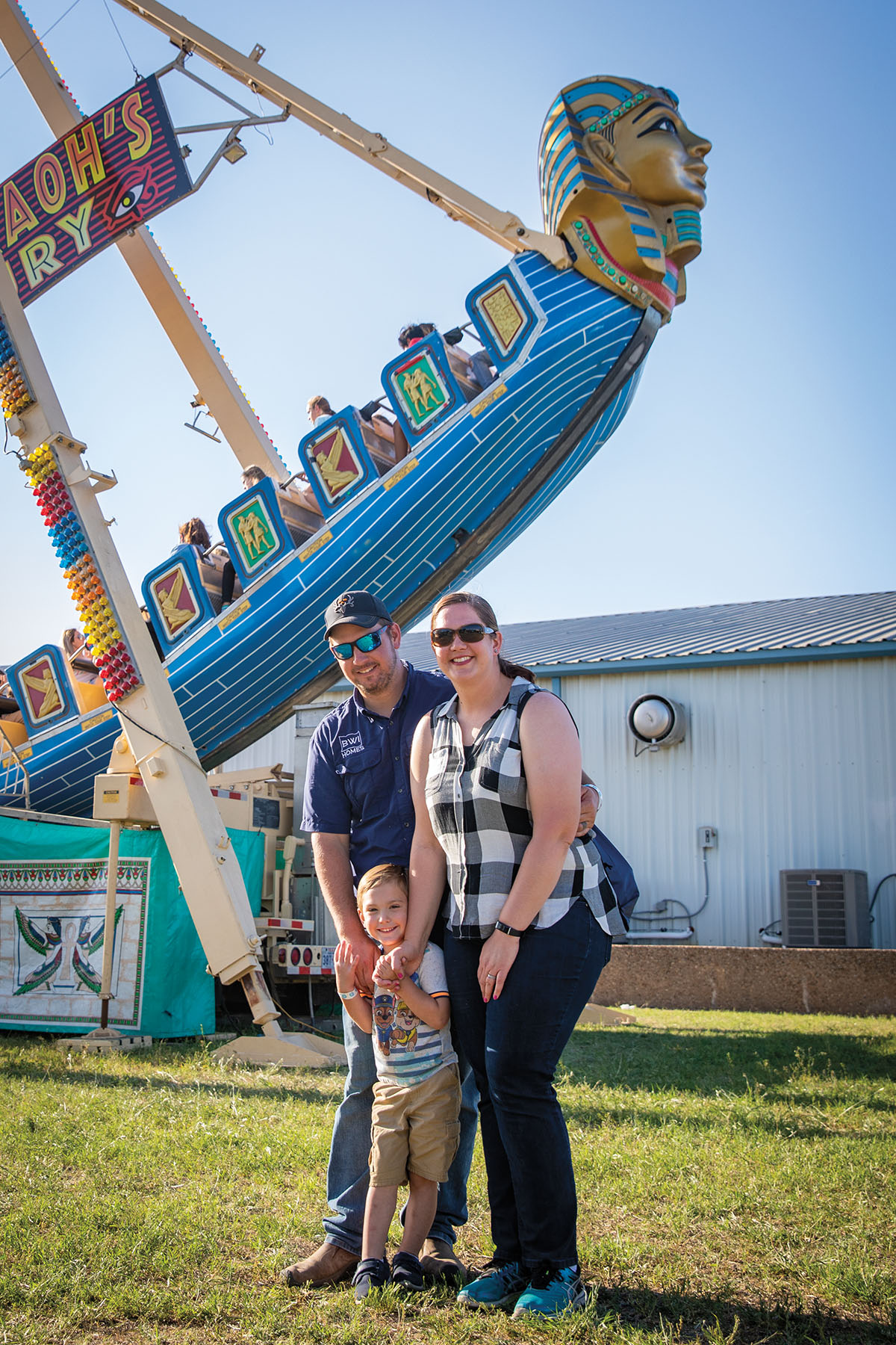 A group of people stand in front of a bright blue carnival ride