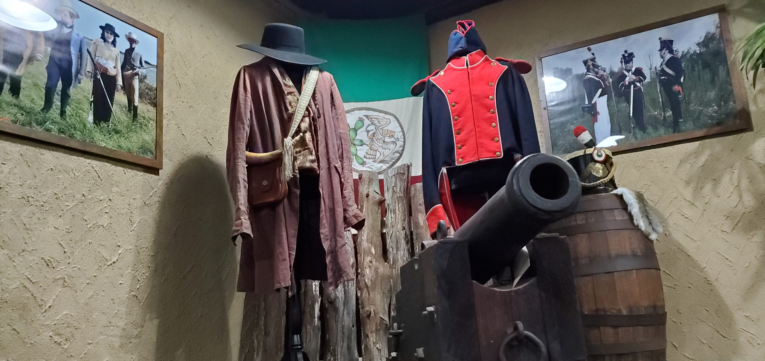 An exhibit showing period clothing, a canon, and photographs