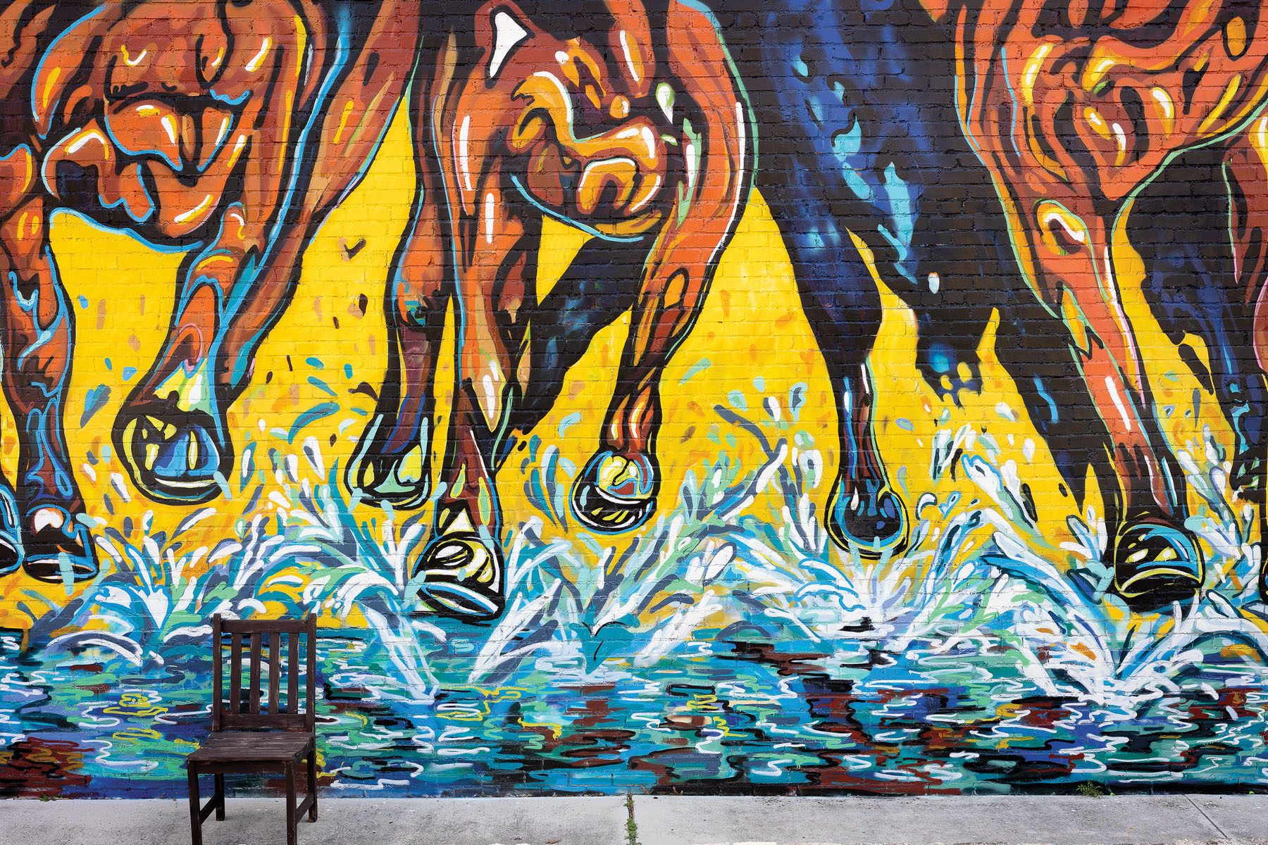 A bright yellow and blue mural of horses hooves running through water