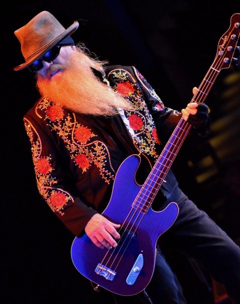 A man with a bright orange beard holds an electric guitar