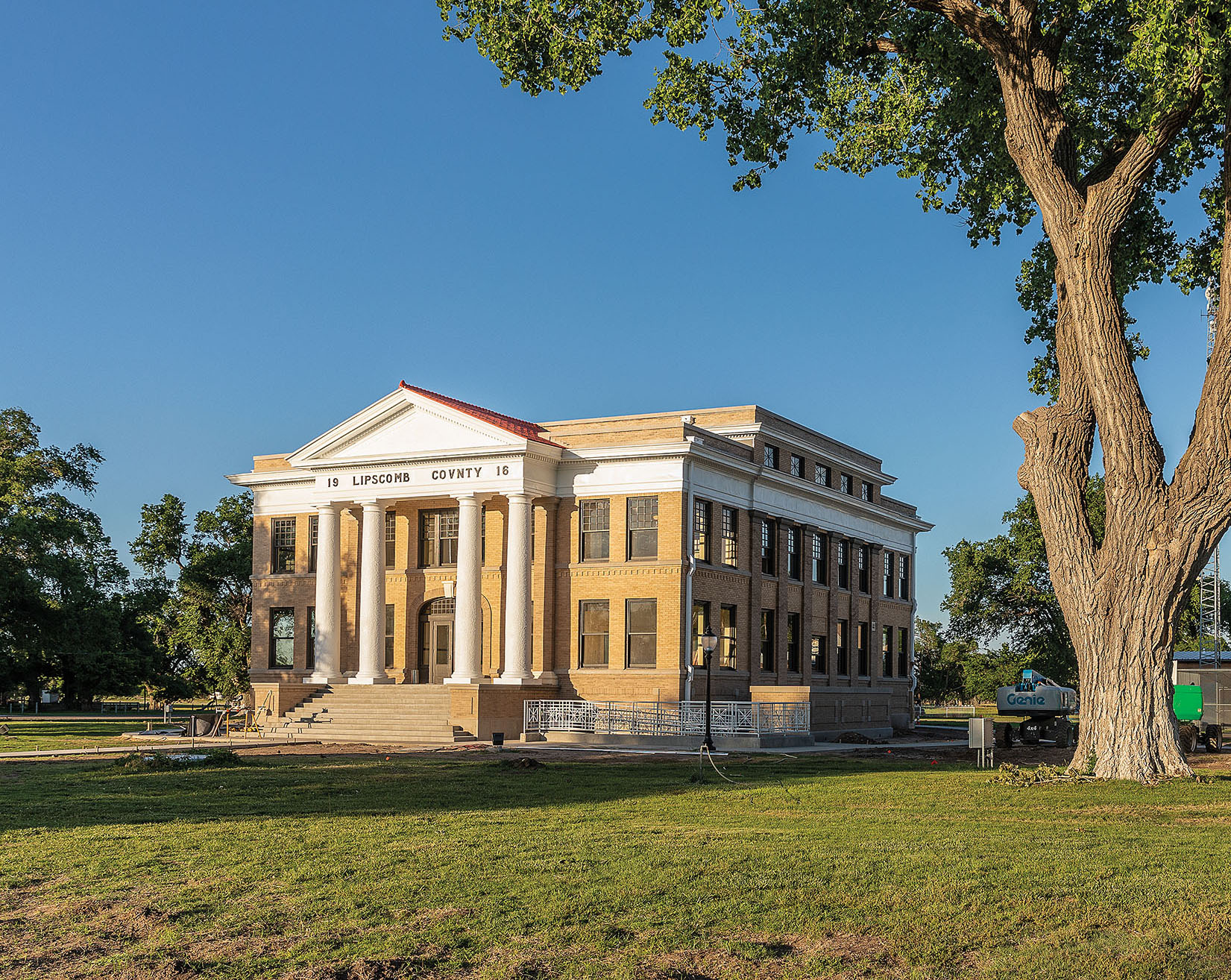 A view of a gold brick courthouse under a tree