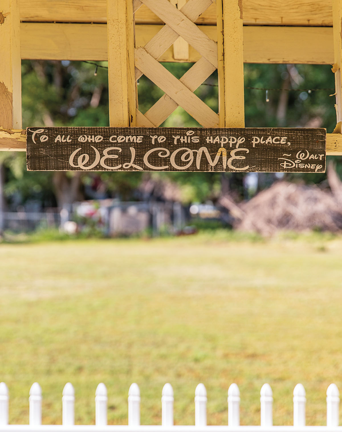 A small wooden sign reading "To All Who Come to this Happy Place, Welcome - Walt Disney"