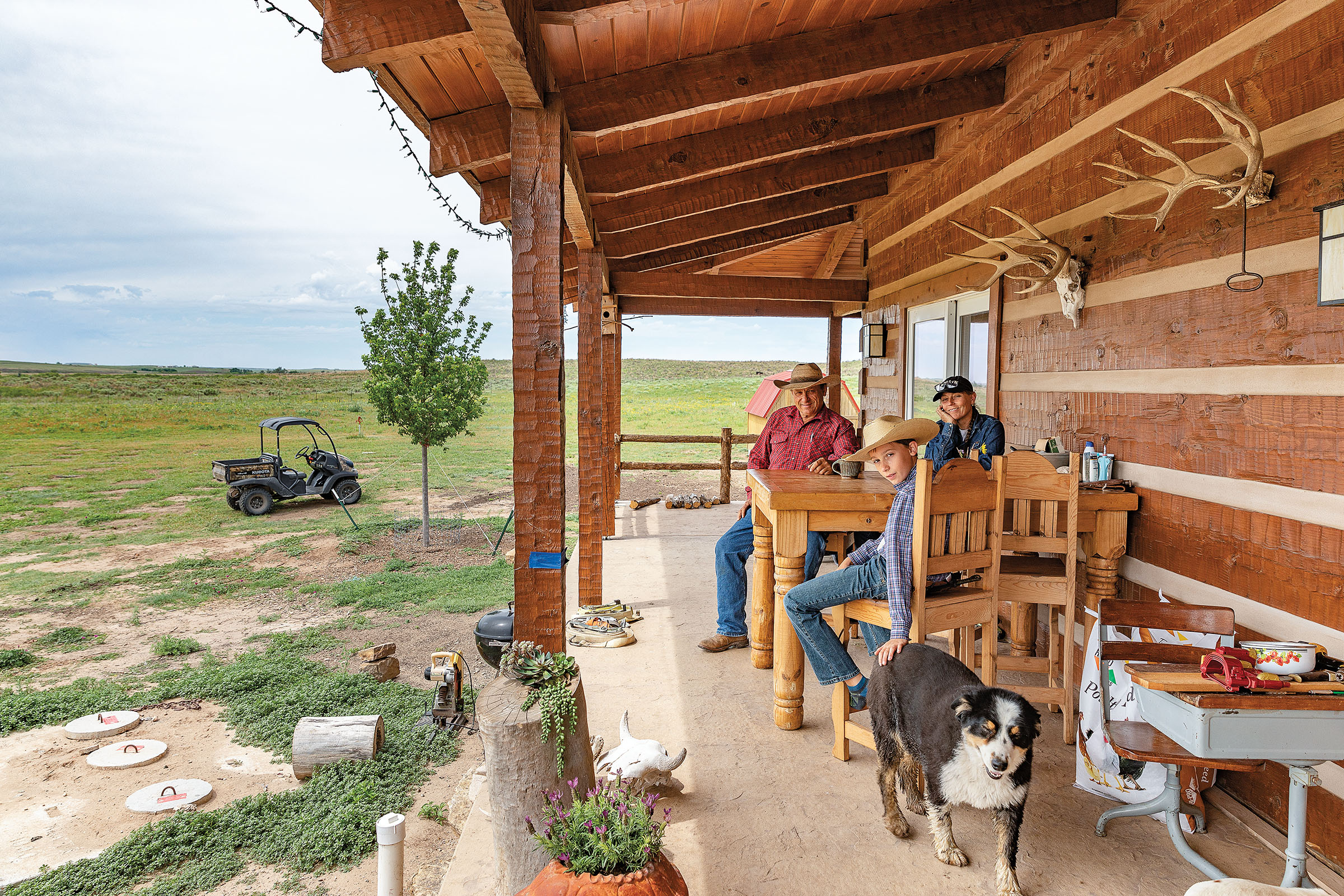 A group of people sit on a porch under an awning