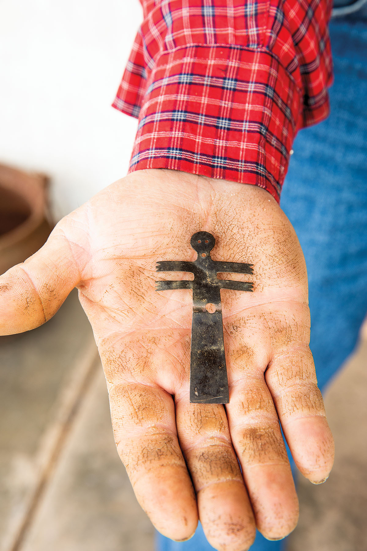 A person holds a dark metal figure in their oustretched palm