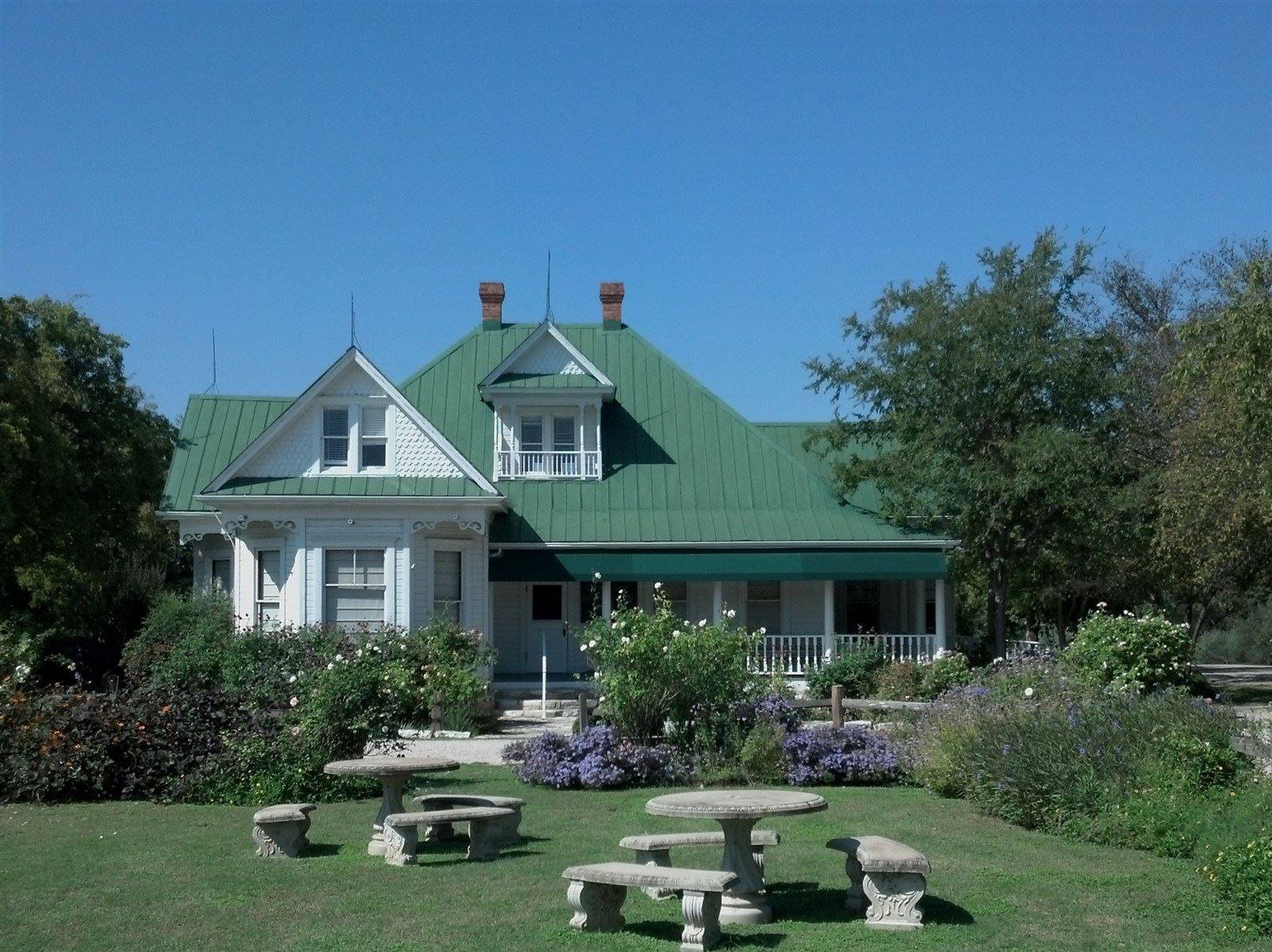 A large white house with a green roof under blue sky