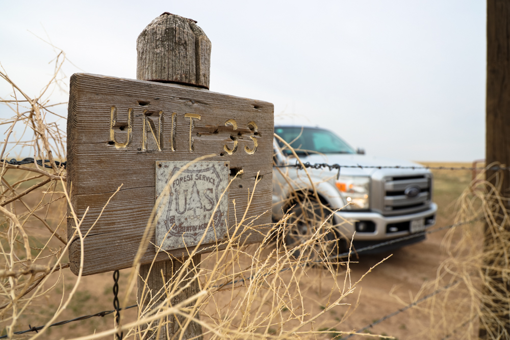 A truck parked next to barbed wire reading "Unit 33"