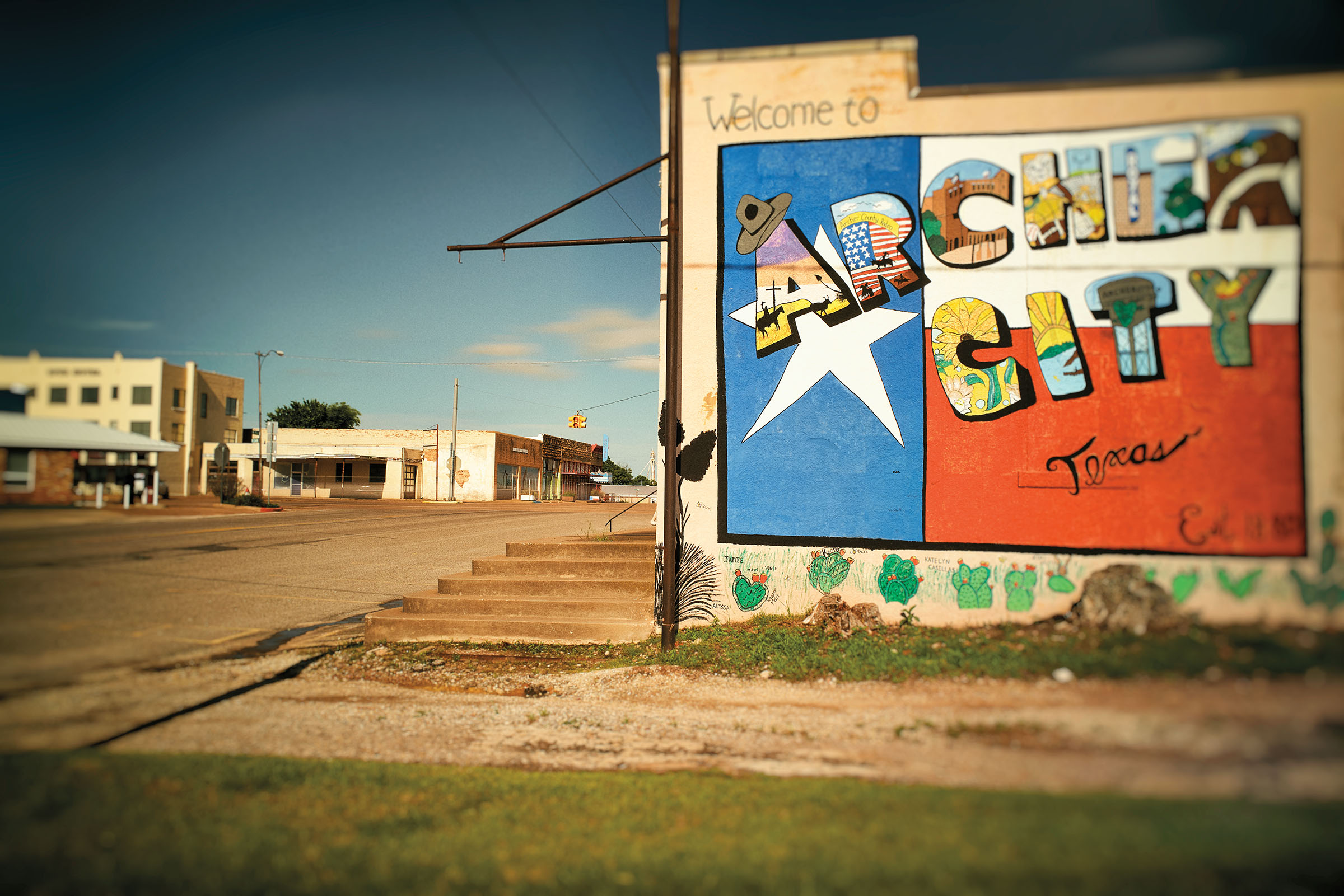 A Texas-flag themed mural reading "Archer City" on the side of a tan building
