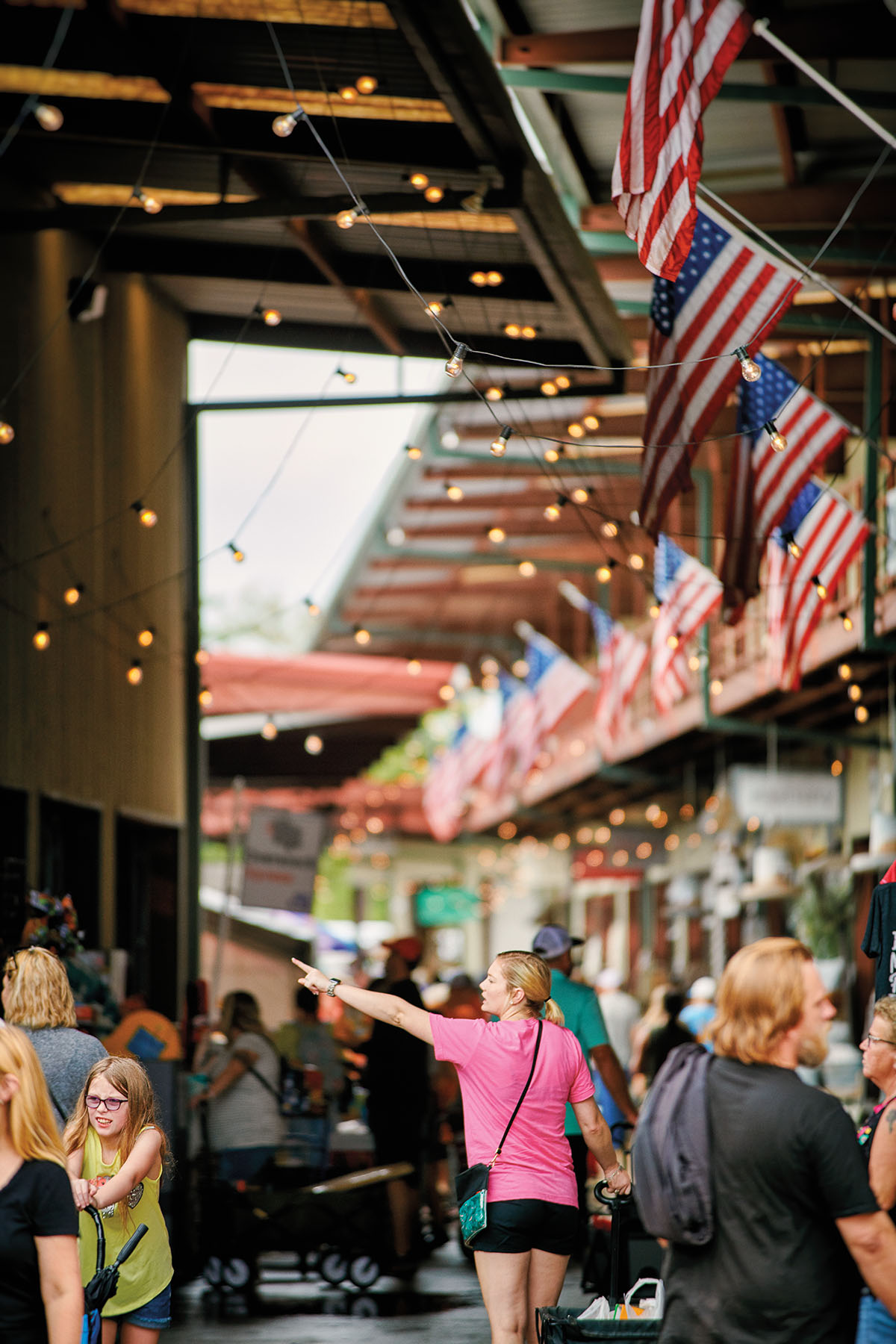 A woman in a pink shirt walks down a crowded market