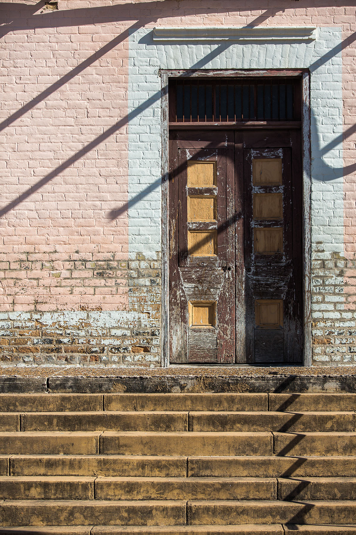 A faded wooden door surrounded by white and pink brick