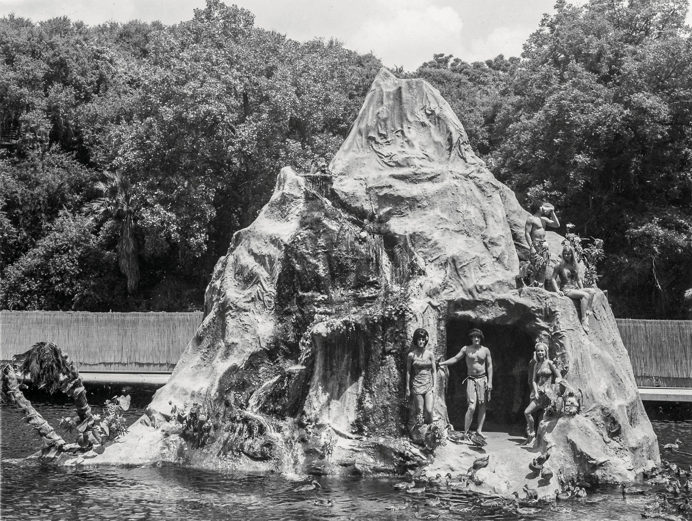 A black and white photo showing people standing in front of a volcano prop