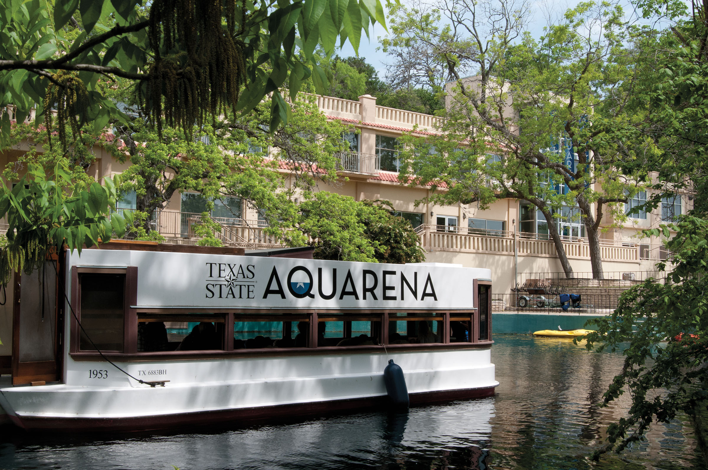 A boat reading "Texas State Aquarena" floats down a river