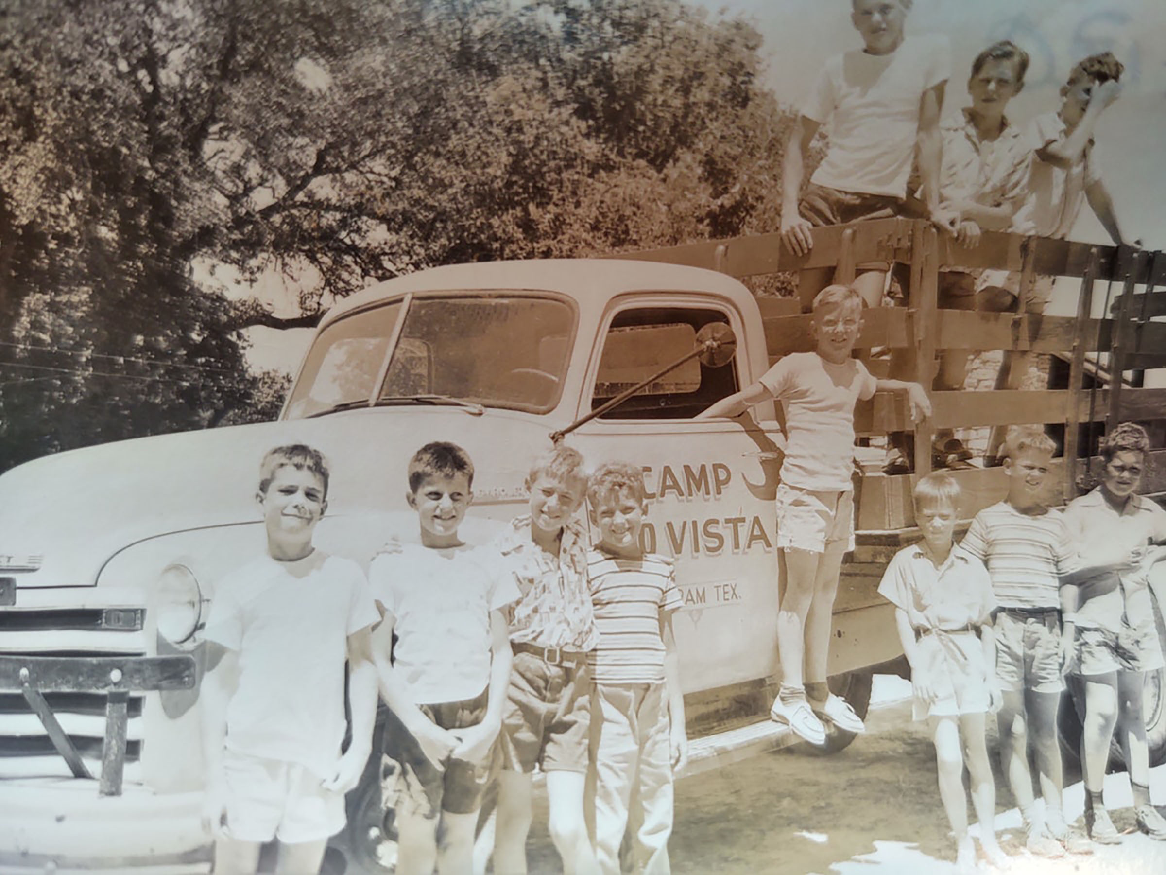 Vintage photo of campers posing in front of an old timey tuck.
