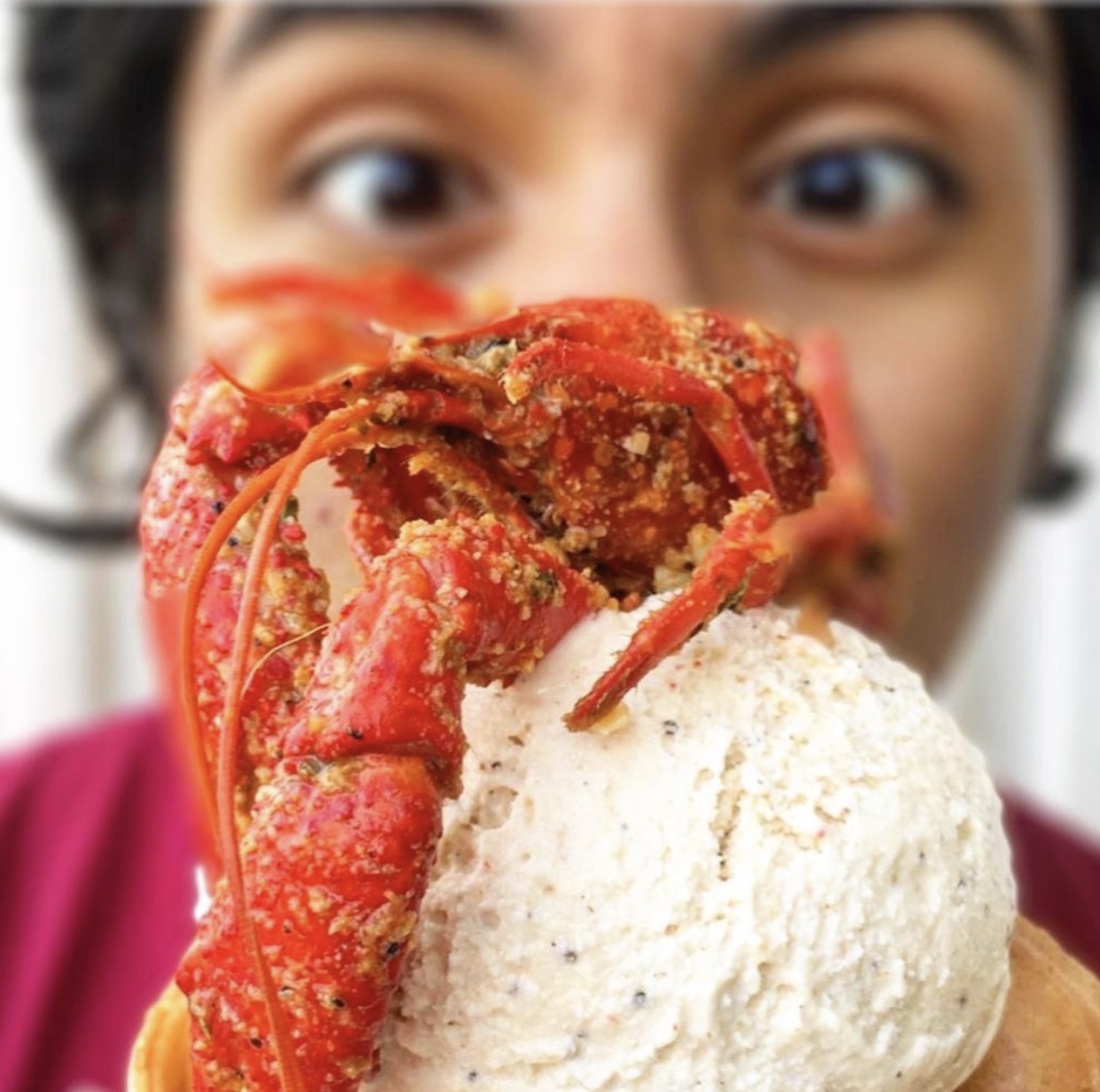 woman holding ice cream cone with a crawfish on top