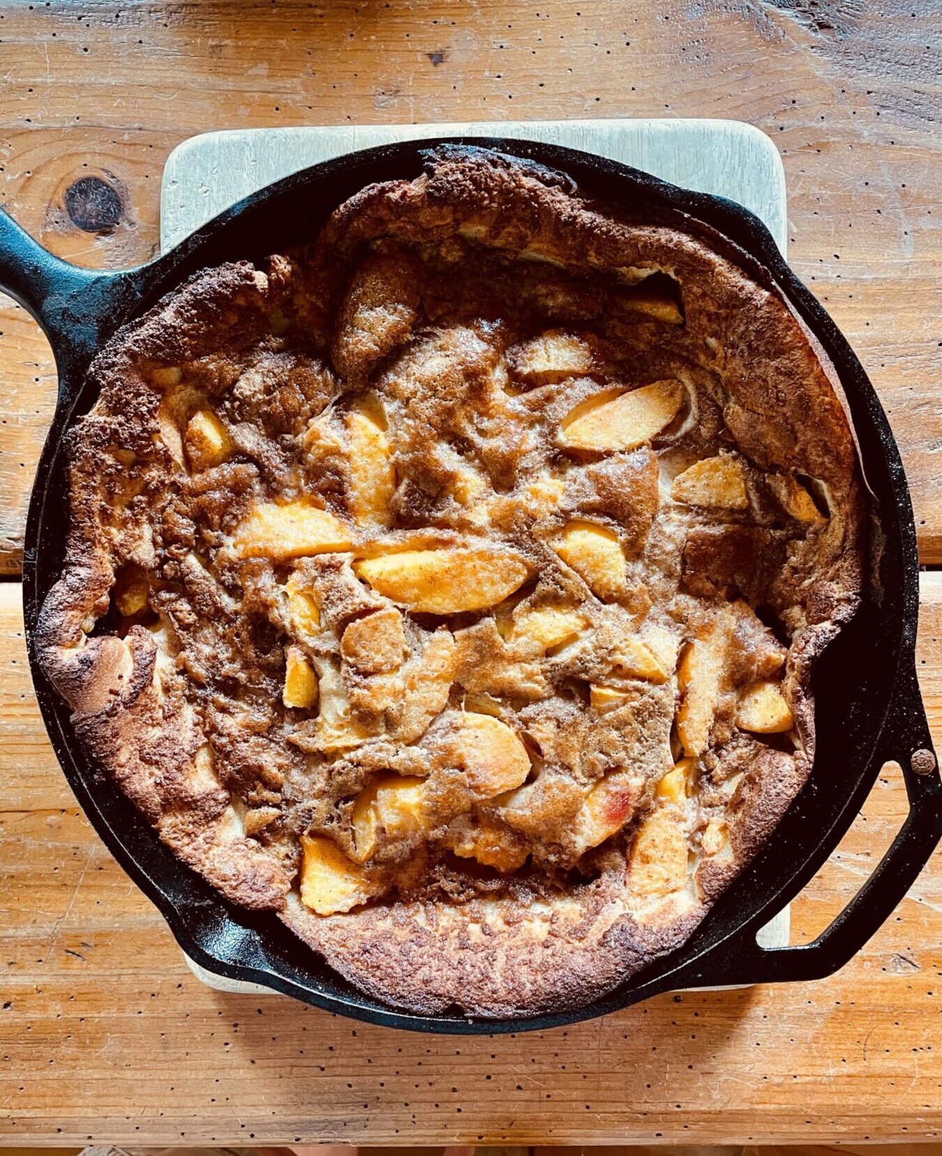german pancake with peaches in a cast-iron skillet