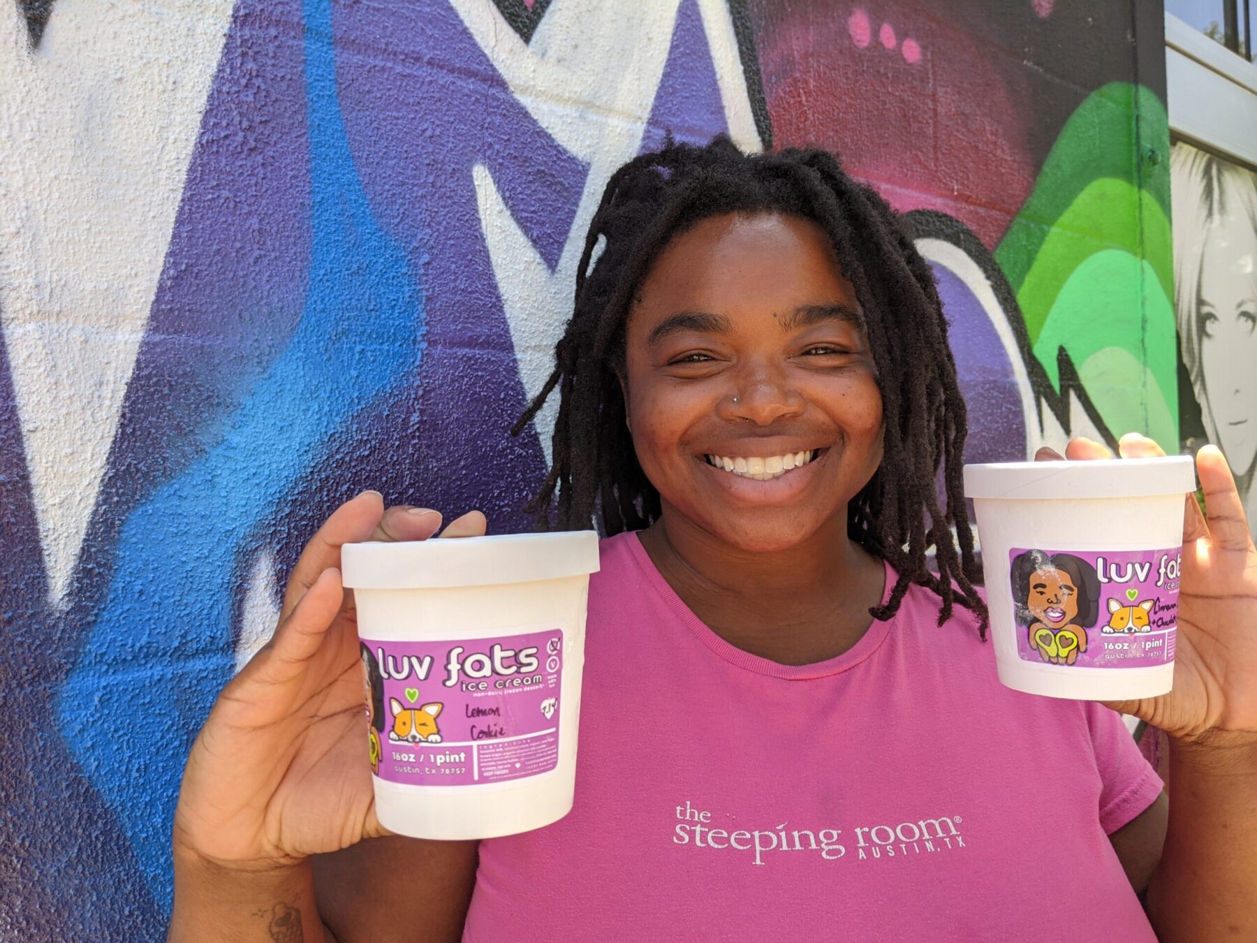 chi ndika holding pints of ice cream outside a mural