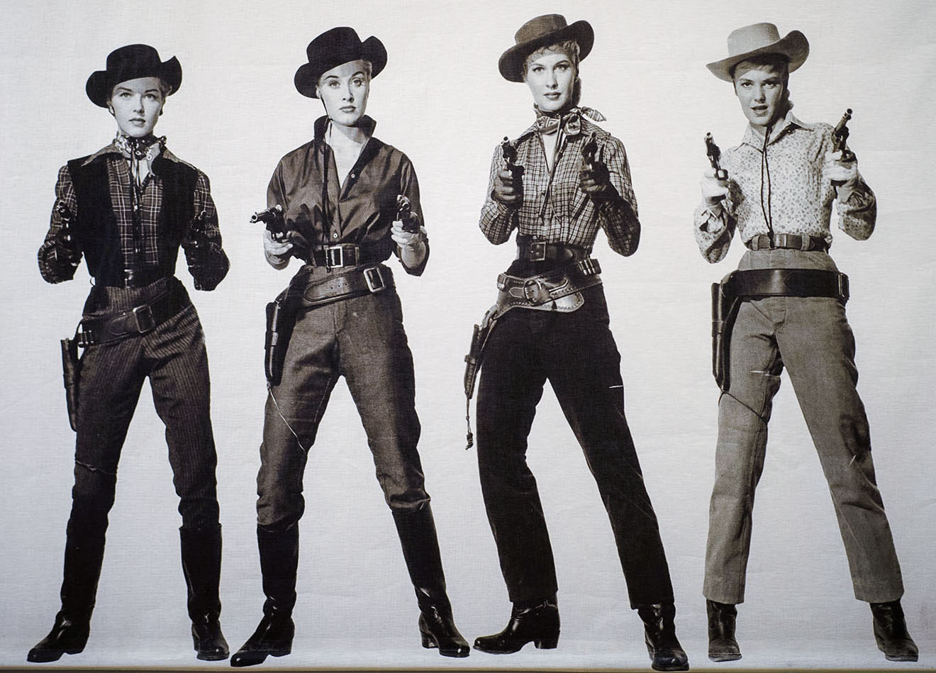 A black and white group of cowgirls standing with guns drawn toward the camera