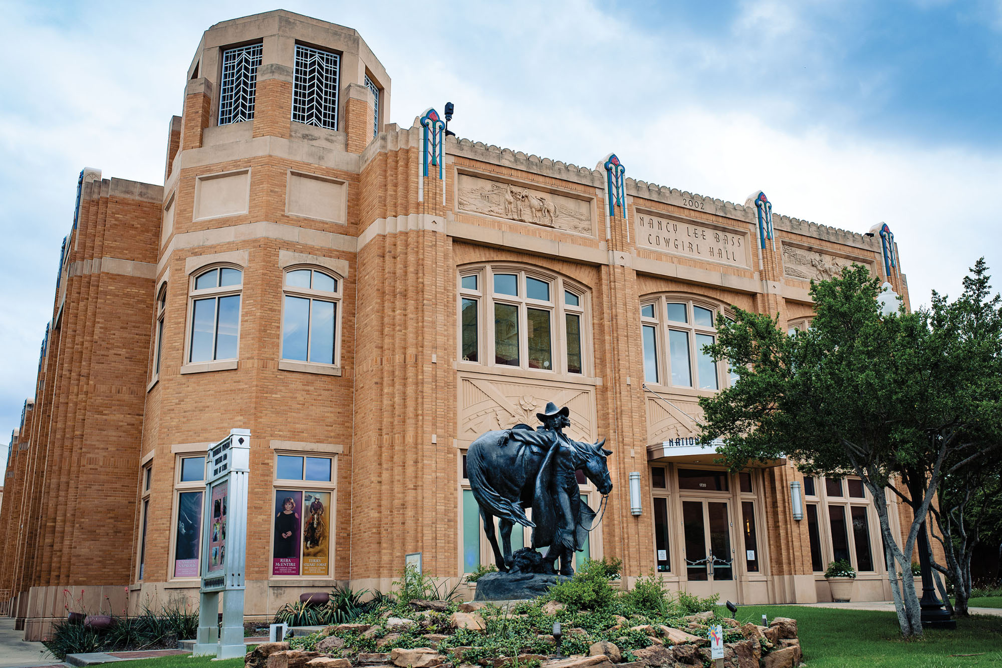 The outside of a red brick building with a dark statue in front