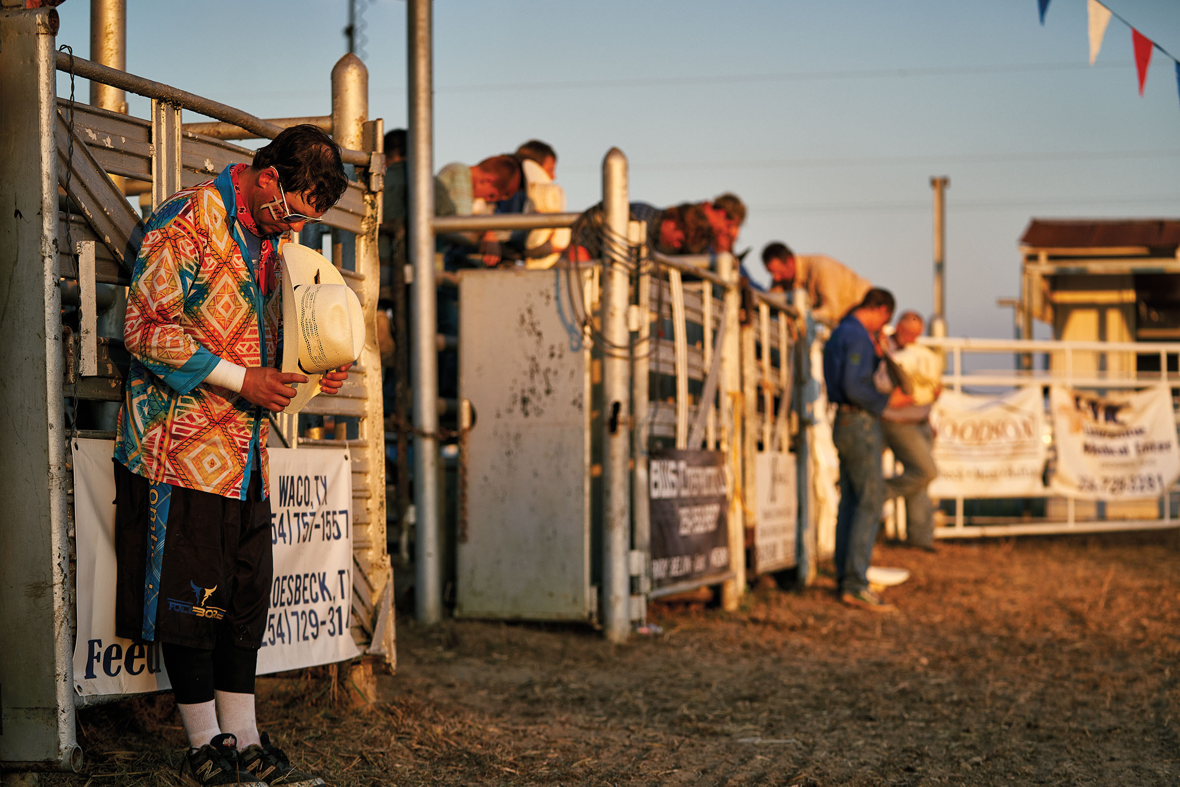 A group of rodeo clowns bow their heads and remove their hats in prayer