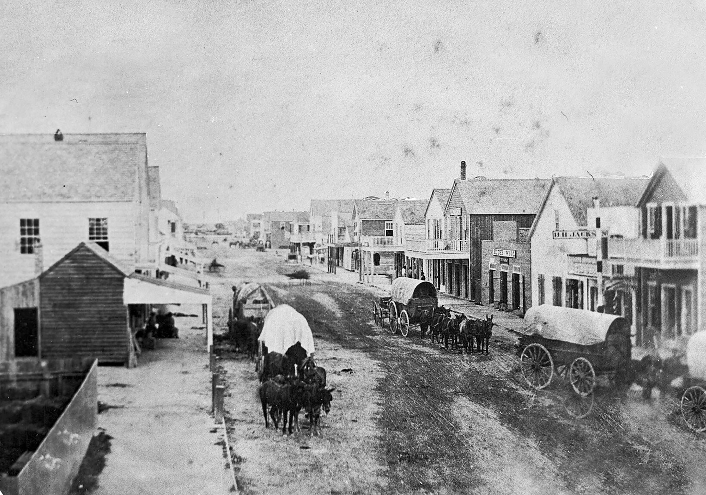 An overhead view of horses and old buildings on a historic street with mud road