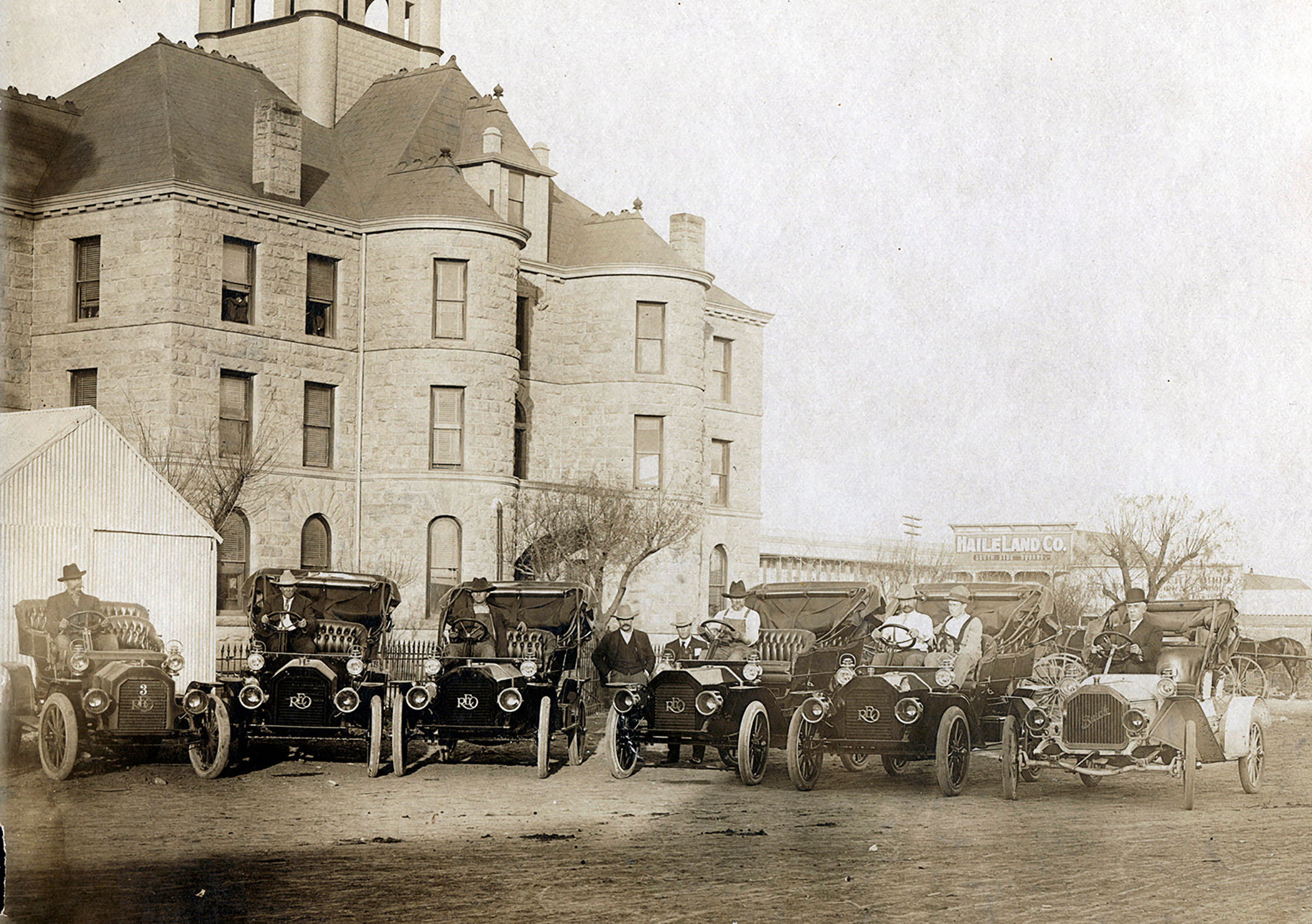 A group of men in cars out front of a courthouse
