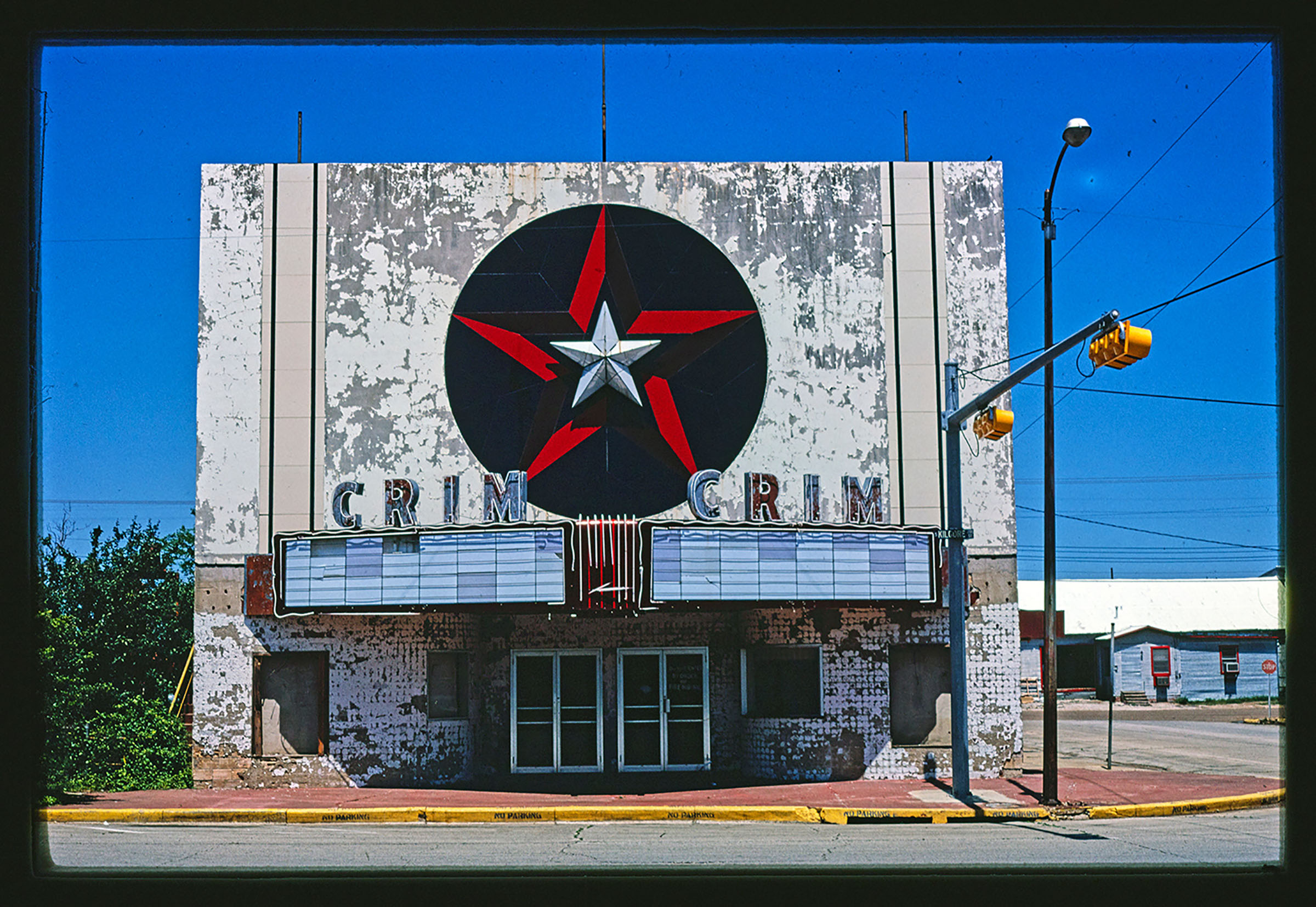 The outside of a theater with peeling paint reading 'CRIM'