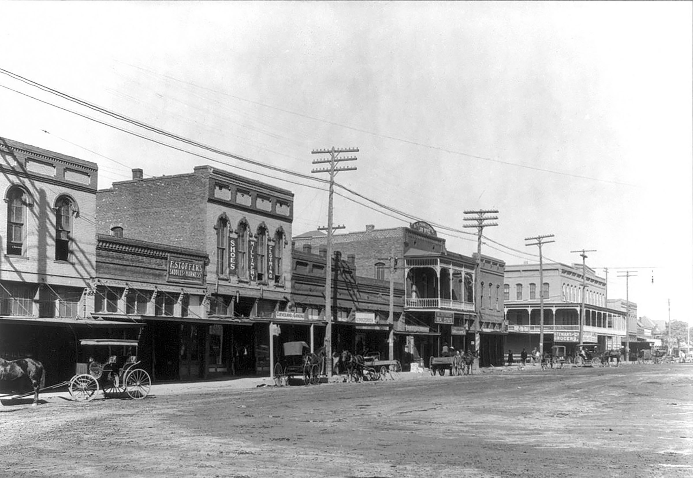 A collection of brick buildings and powerlines on a dirt main street