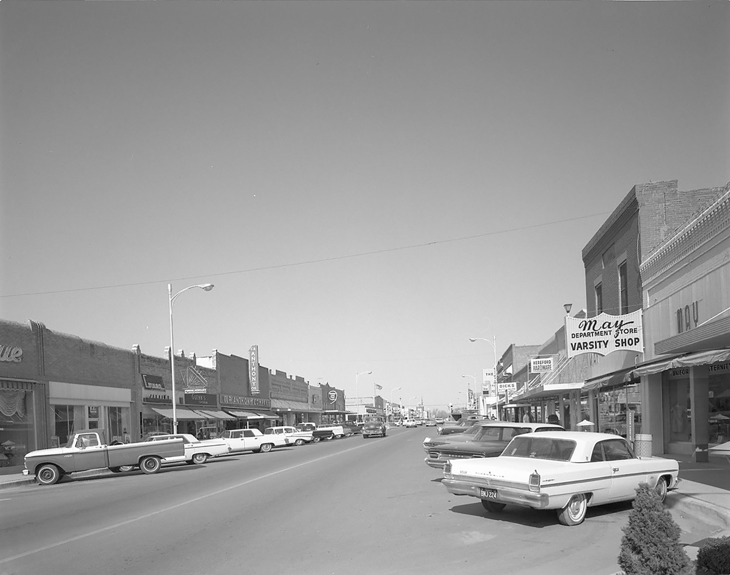 Cars line a street with shops, one reading May Department Store Varsity Shop
