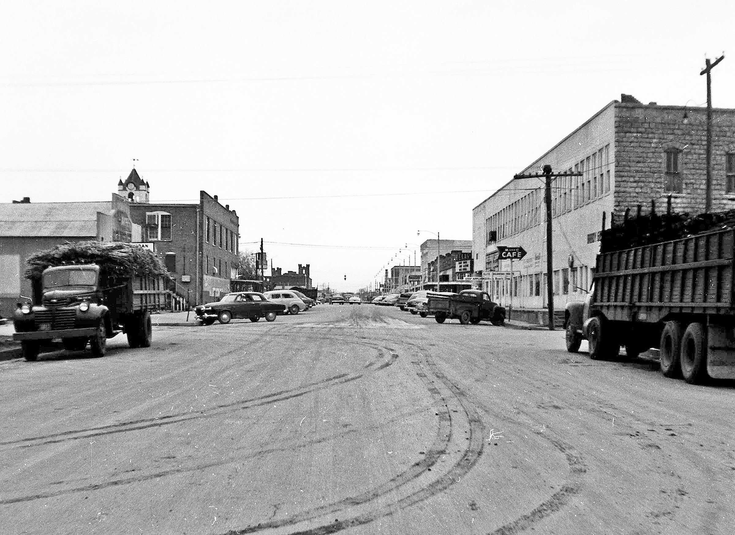 A collection of vehicles along a dirt main street.