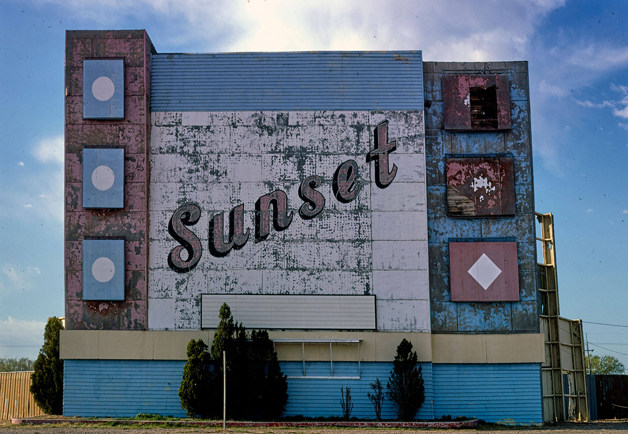 A tall blue red and white building reading 'Sunset'