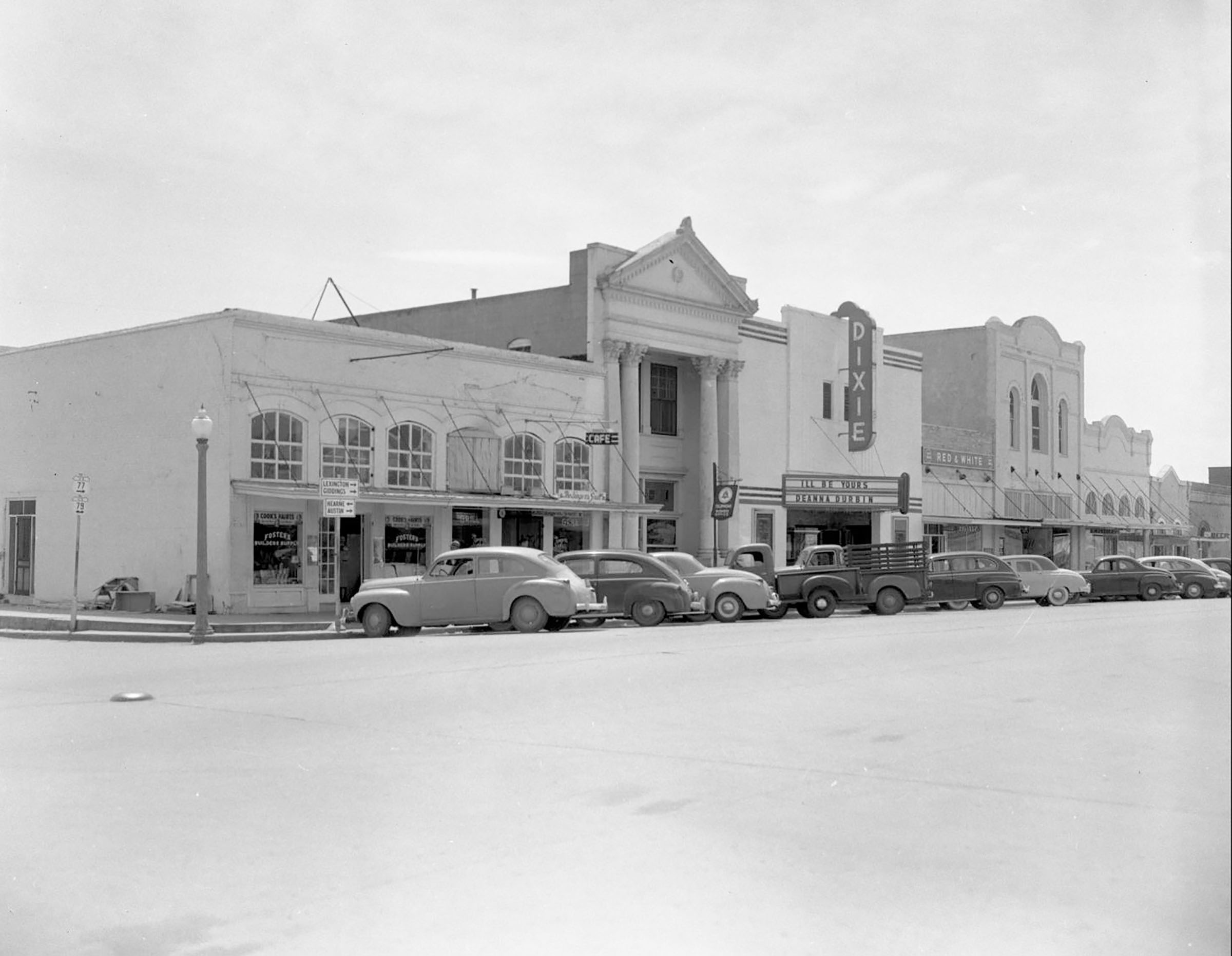 Old cars line a historic main street with a theater marquee reading 'DIXIE'