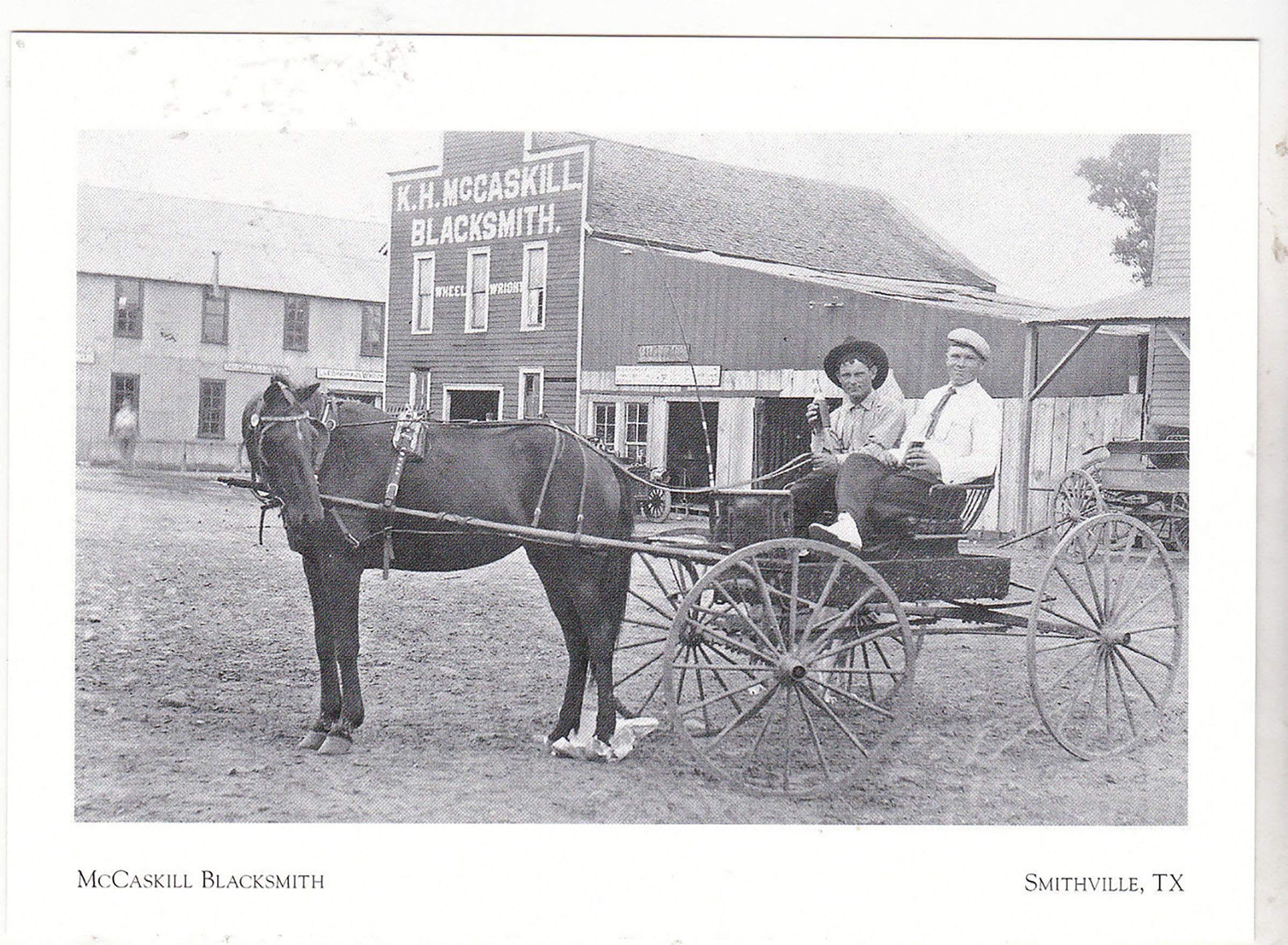 Two men sit in a wagon pulled by a horse turning his head in front of buildings'