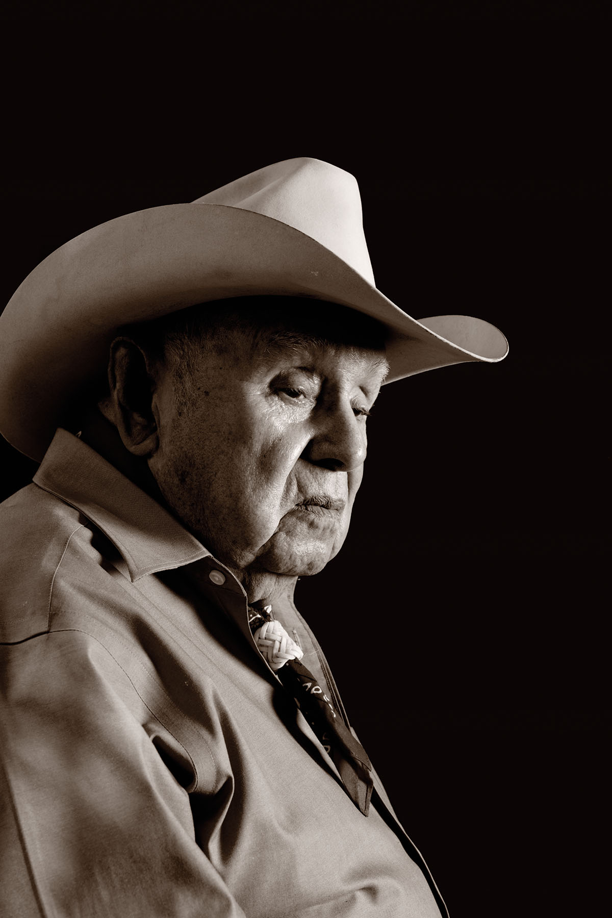 An older man in a cowboy hat looks somber