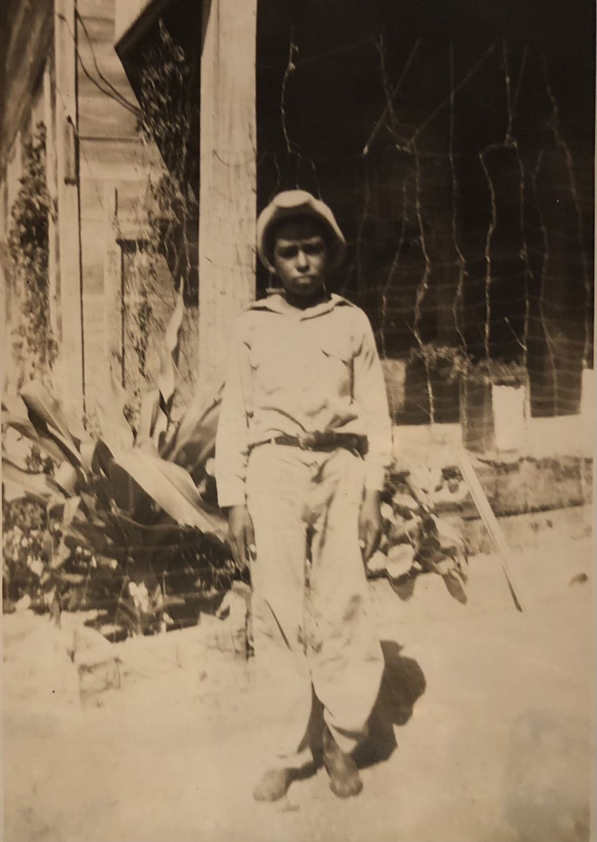 A sepia-tone portrait of a young man in white with a belt