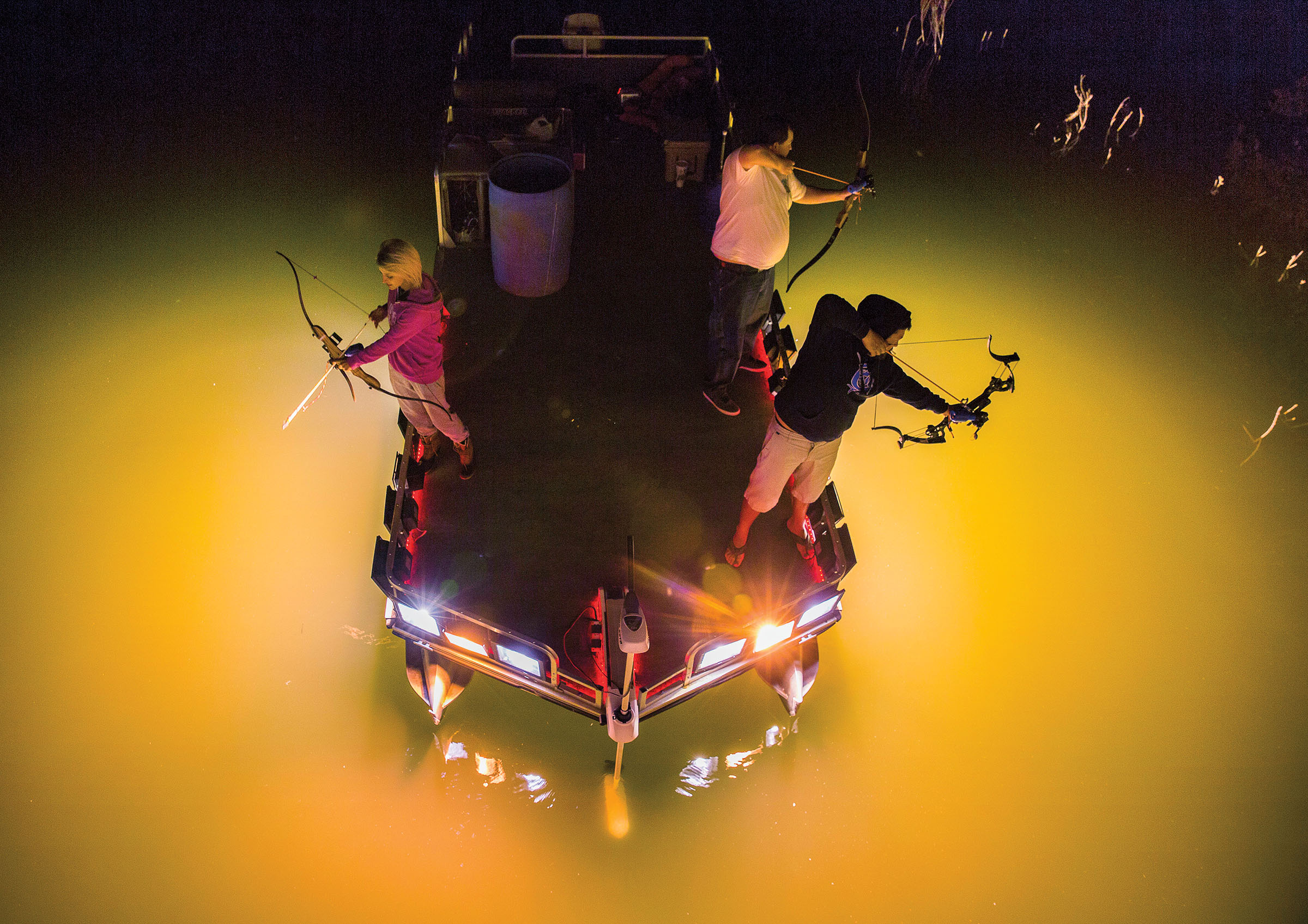 A group of people lean out of a boat surrounded by bright lights