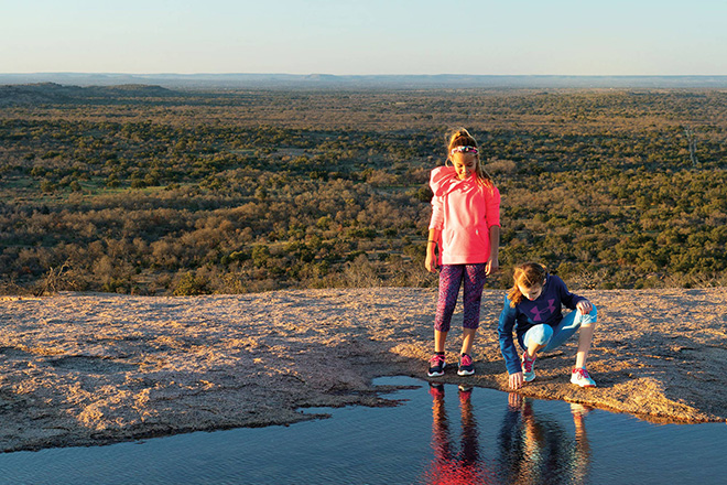 Two young people look into a pool of water looking down on a vast landscape