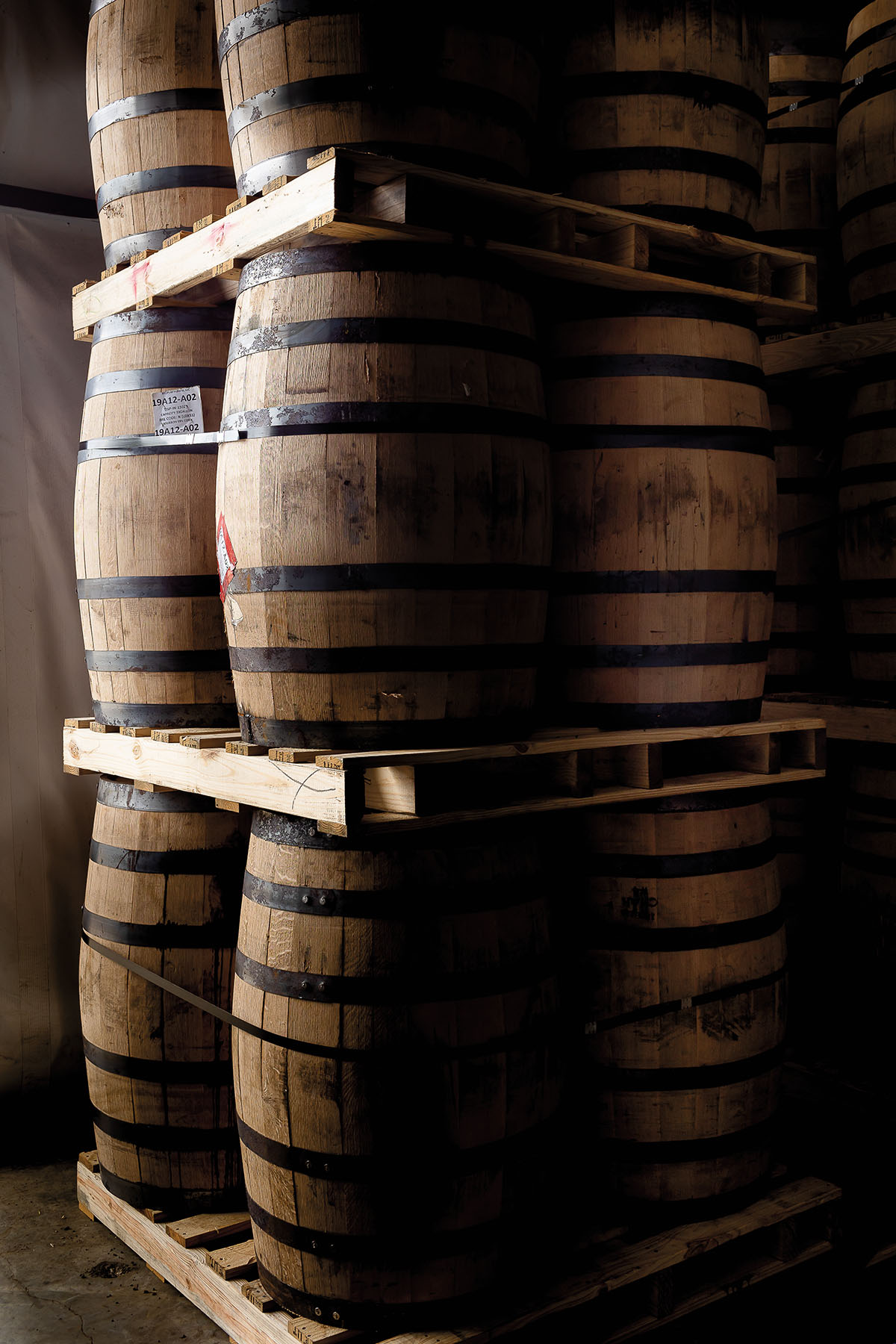 A dark picture of barrels stacked on wooden pallets