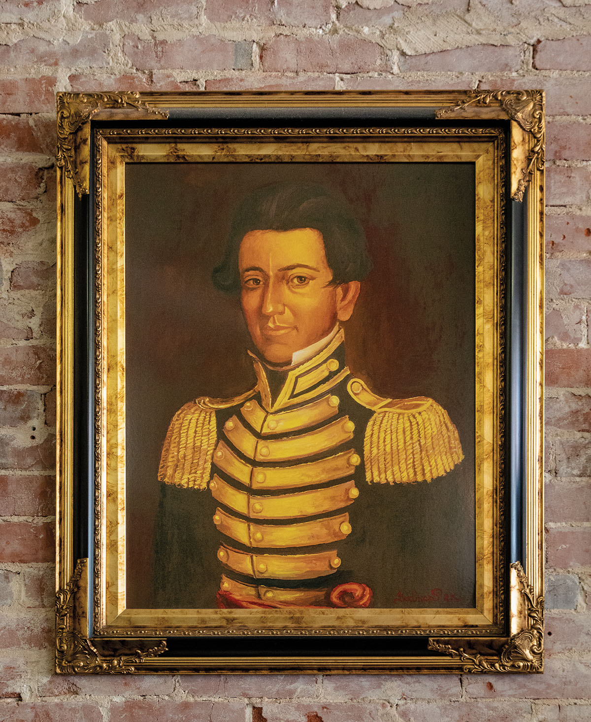 A portrait of a man in gold-adorned shoulder pads and a jacket. Picture hangs on a faded brick wall