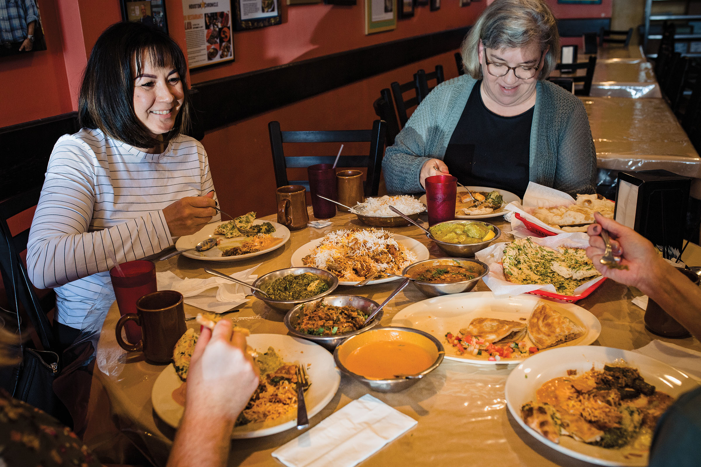 A table of guests seated around a large selection of Indian food on plates and in silver dishes