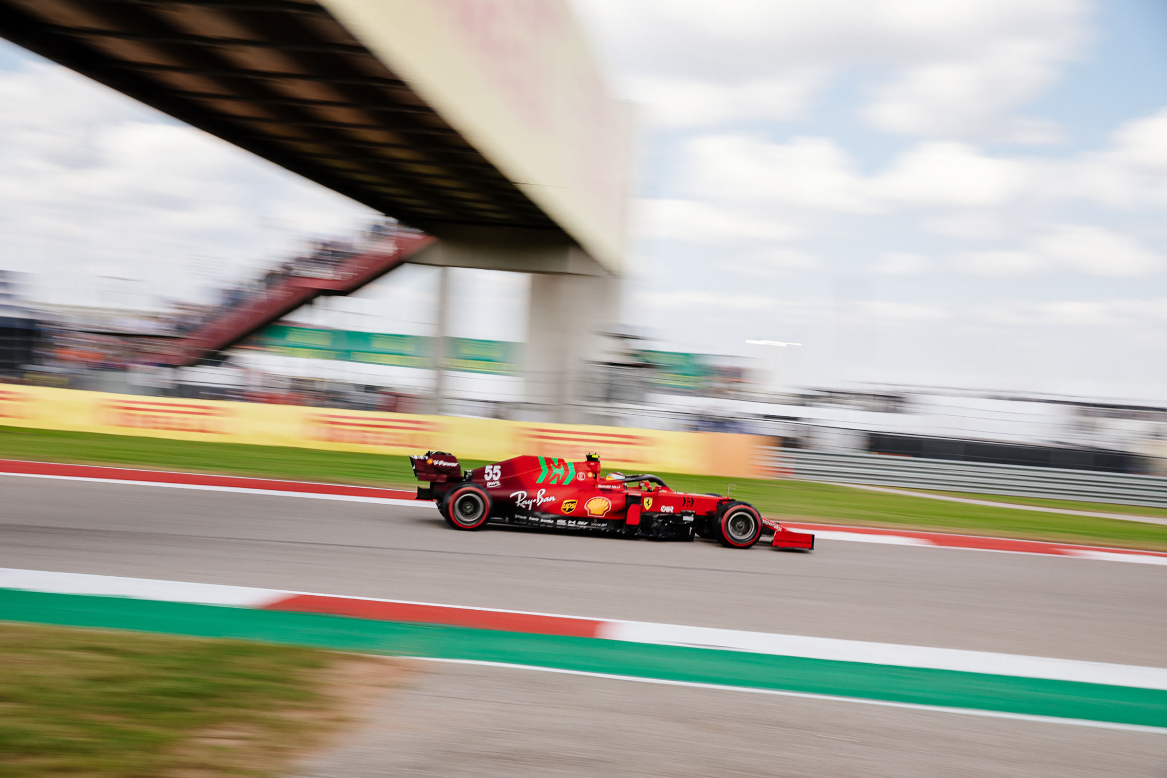 A red and green car whizzes by a green track with motion blur