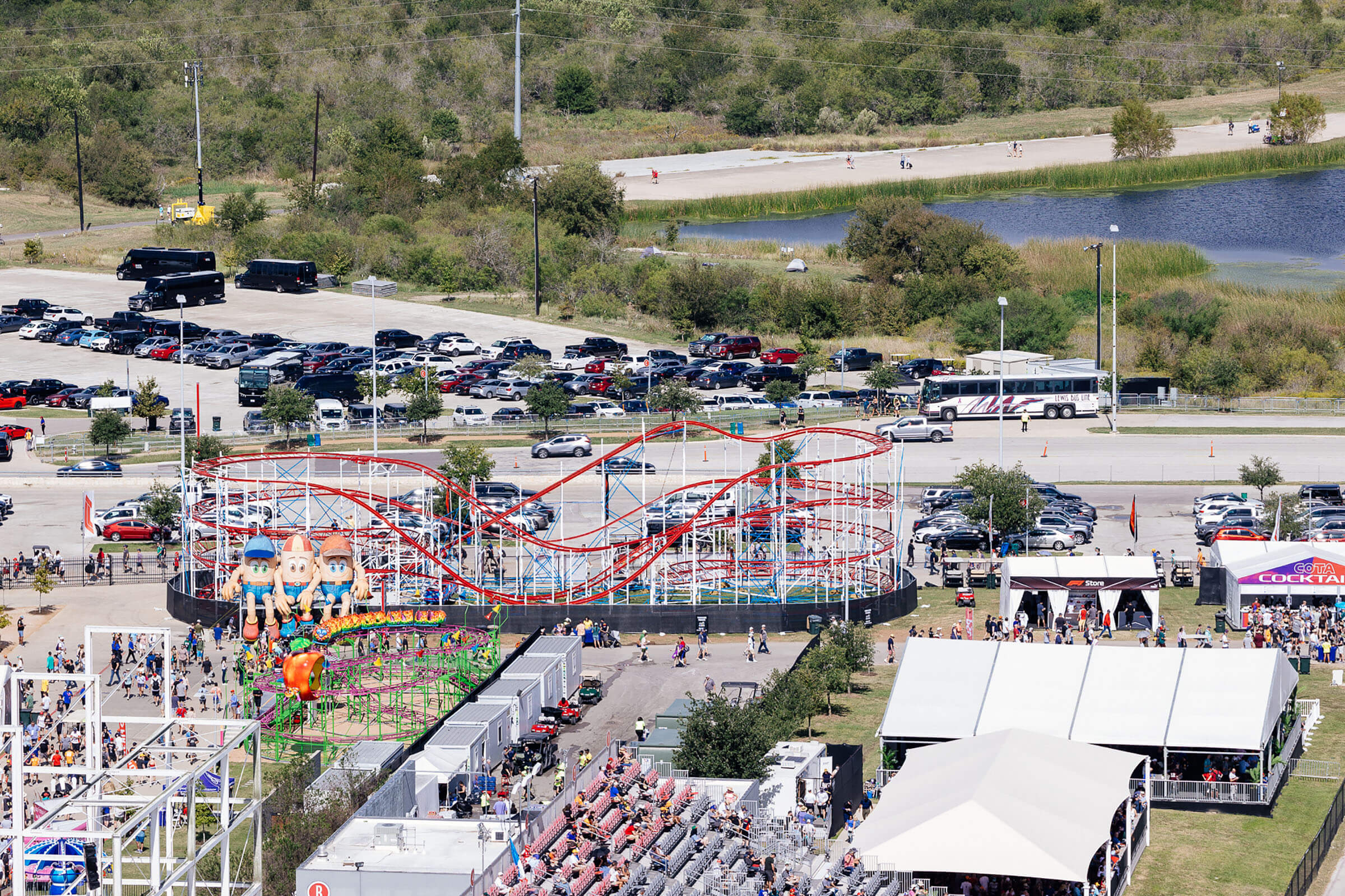 An overhead view of people enjoying carnival games and rides in a sunny parking lot